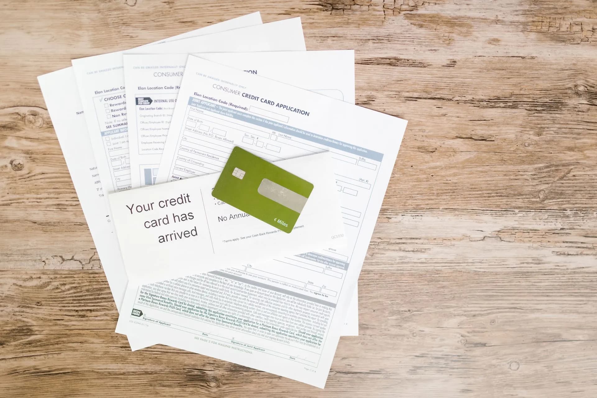 Top view of credit card and application documents on wooden surface, illustrating AI agent hacking campaign breached at least 27 companies and took 600,000 cards, Gambit says