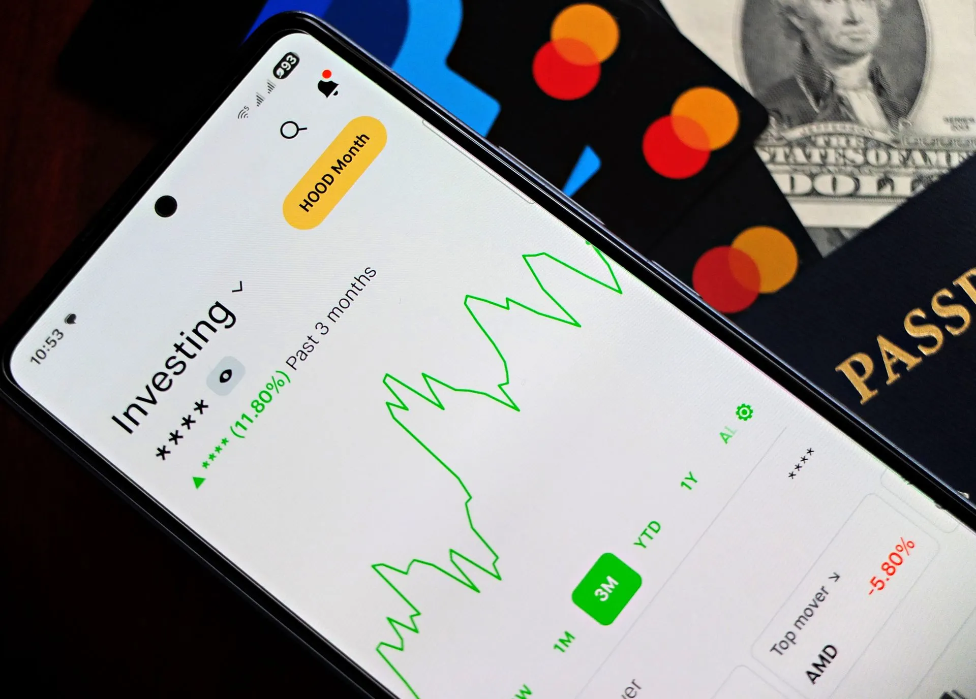 A smartphone showing an investment app with green growth indicators, surrounded by credit cards, US dollars, and a passport, illustrating AI agents in banking can look but not pay at Equals Money