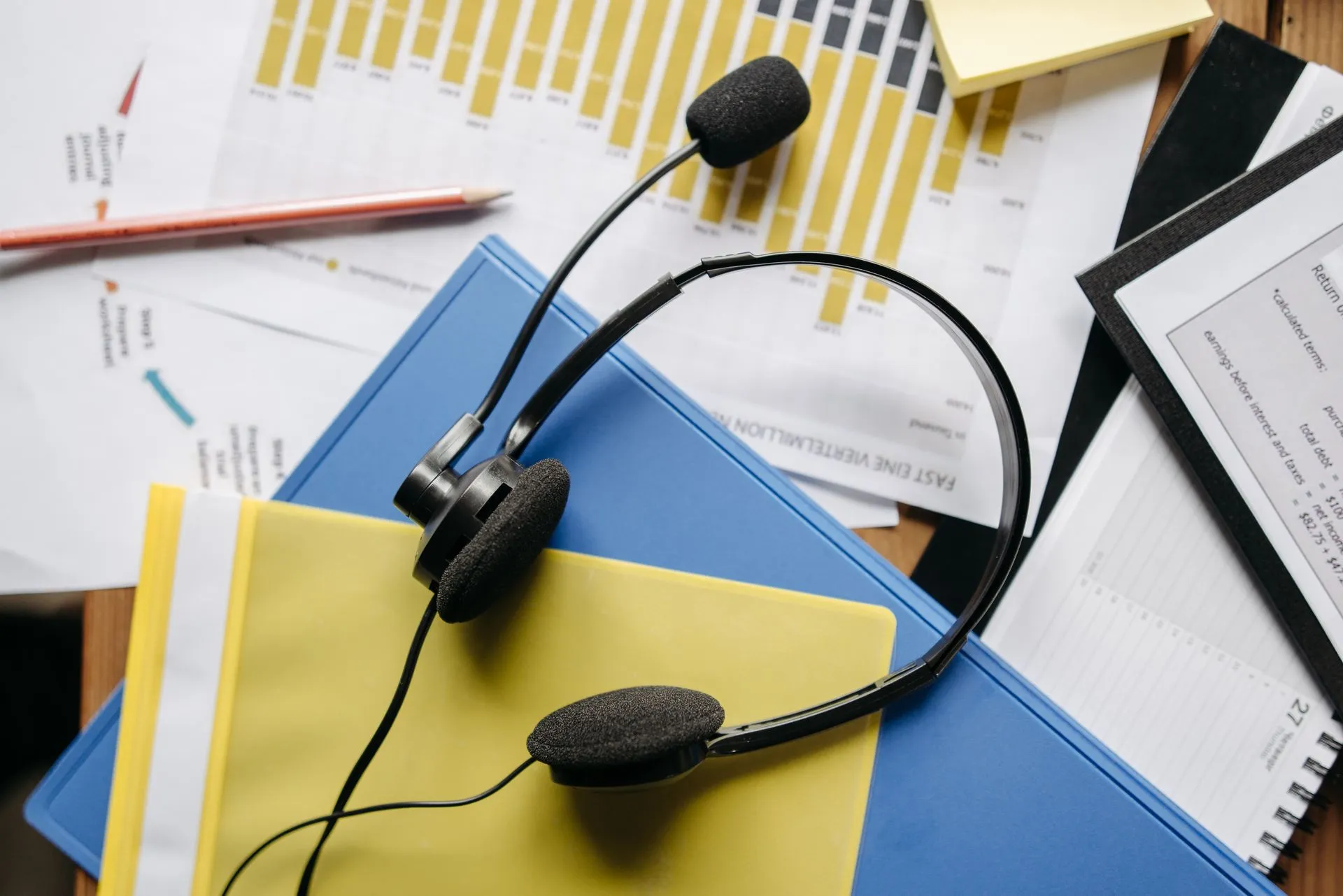 Close-up of an office desk with headset, charts, and documents showcasing customer service support, illustrating Gorgias publishes AI customer service evals, including the categories