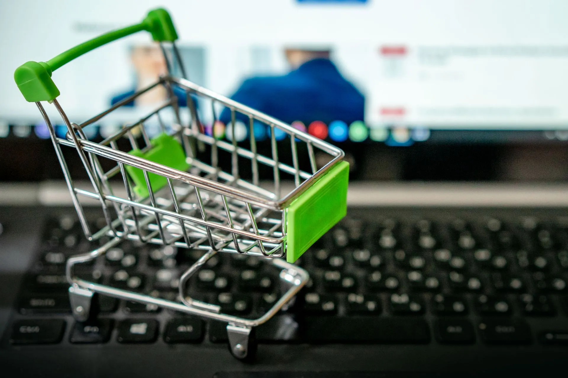 Miniature shopping cart placed on a laptop keyboard, symbolizing online shopping, illustrating AI search brand visibility