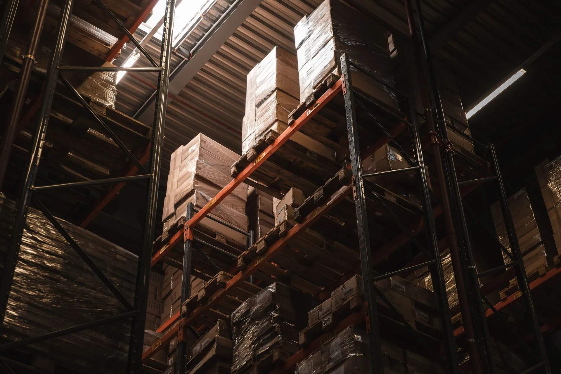 Interior view of a warehouse with stacked cardboard boxes on high shelves, showcasing storage and logistics, illustrating Amazon layoffs hit hundreds in its Stores retail unit after