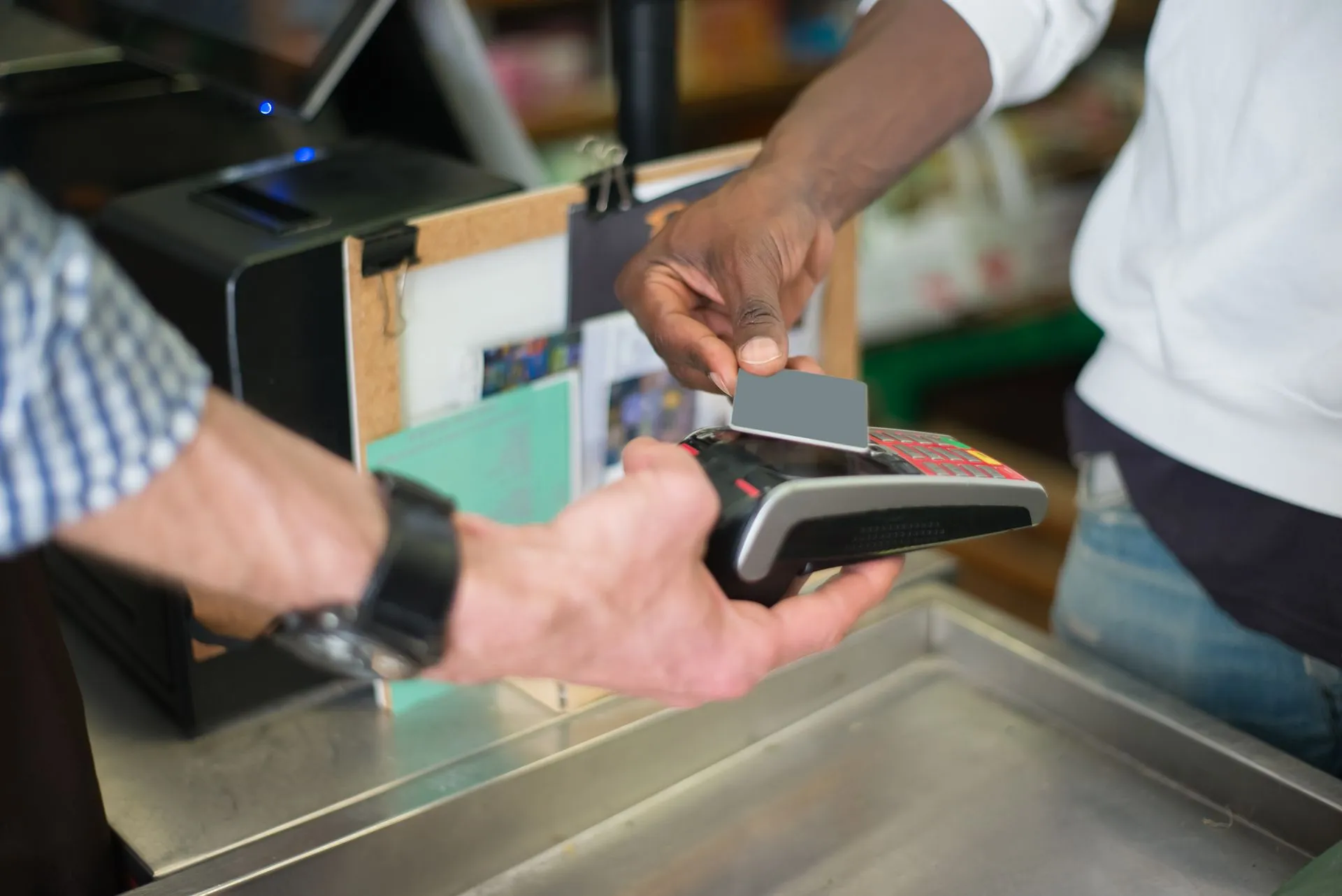 A contactless payment being made using a card reader at a retail store checkout counter, illustrating American Express AML penalty
