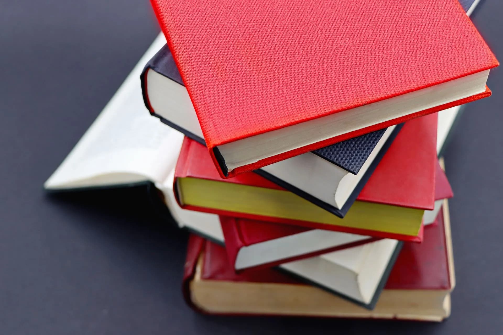 Pile of assorted hardcover books with colorful covers, perfect for study or literature themes.