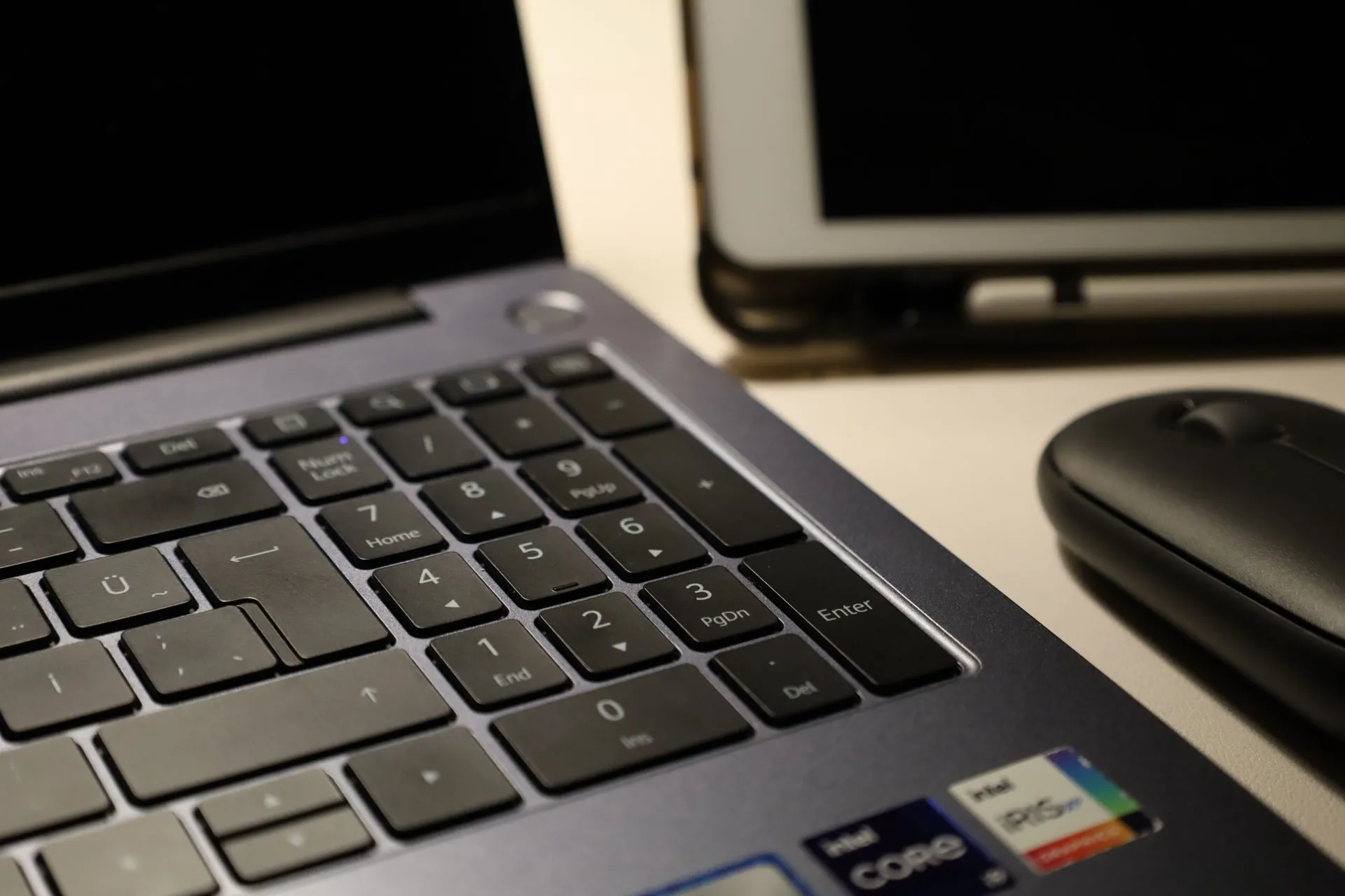 Close-up of laptop keyboard, wireless mouse, and tablet illustrating modern workspace technology, illustrating Anthropic opens cyber models to vetted defenders with three-tier
