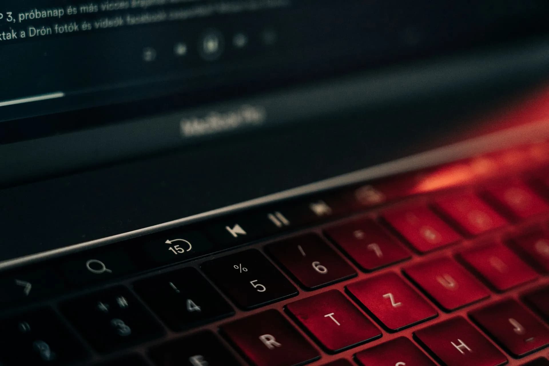 A vibrant close-up of a backlit laptop keyboard with a glowing red hue, showcasing modern technology, illustrating Apple to tighten Full Disk Access over AI agent risks as Google