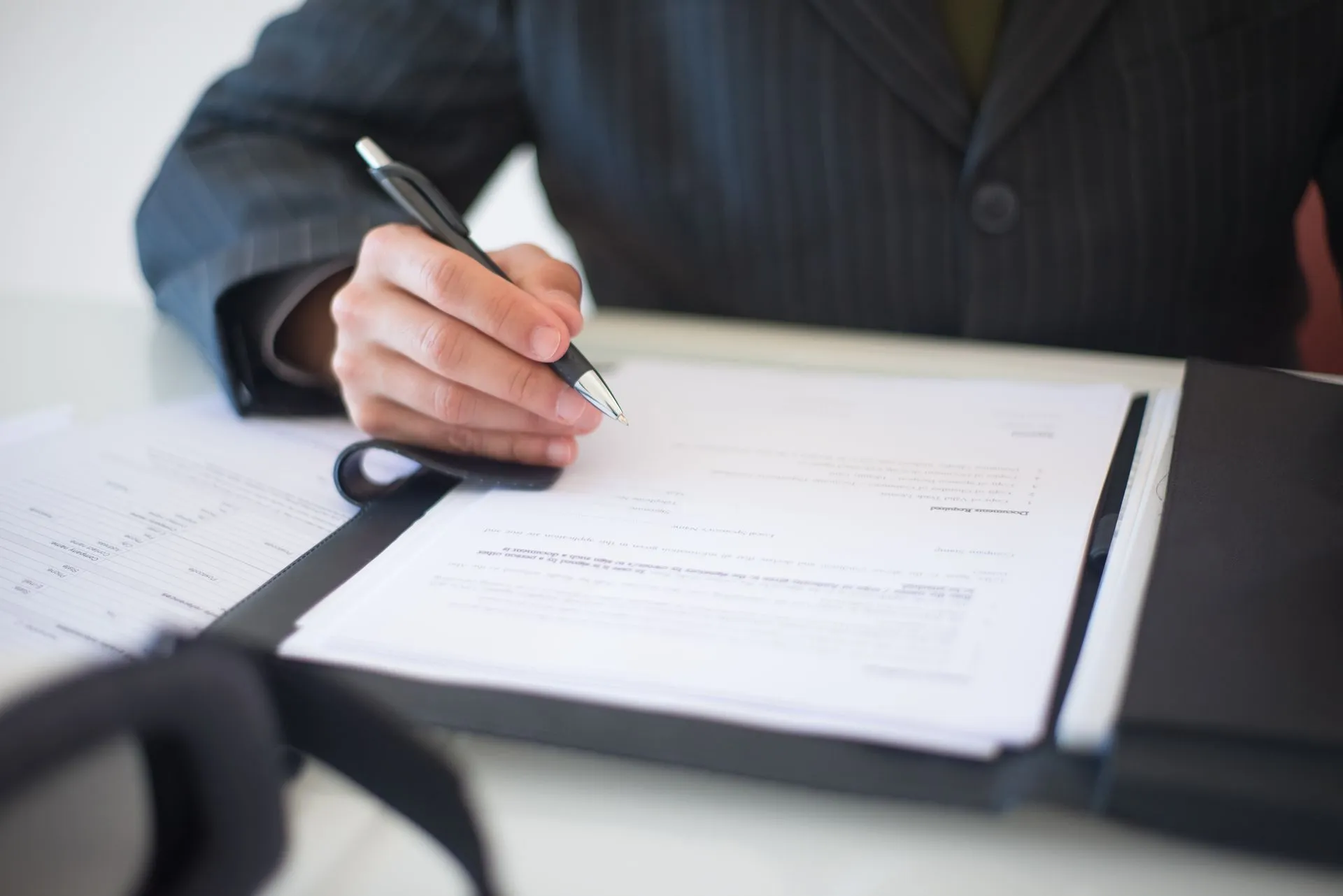 Close-up of a hand signing documents with a pen, symbolizing an important business contract, illustrating Arceus Legal raises $17 million to grow its AI-run law firm beyond contract