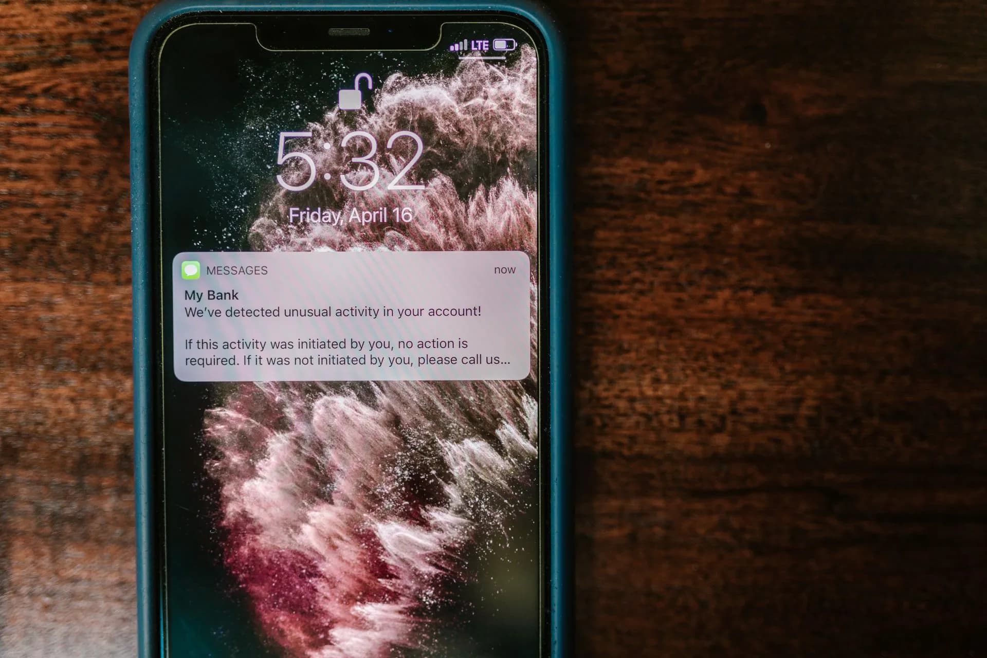 Close-up of a smartphone displaying a bank alert notification on a wooden table, illustrating ASOS confirms customer data breach after hackers push 'ASOS HACKED' alert through its app