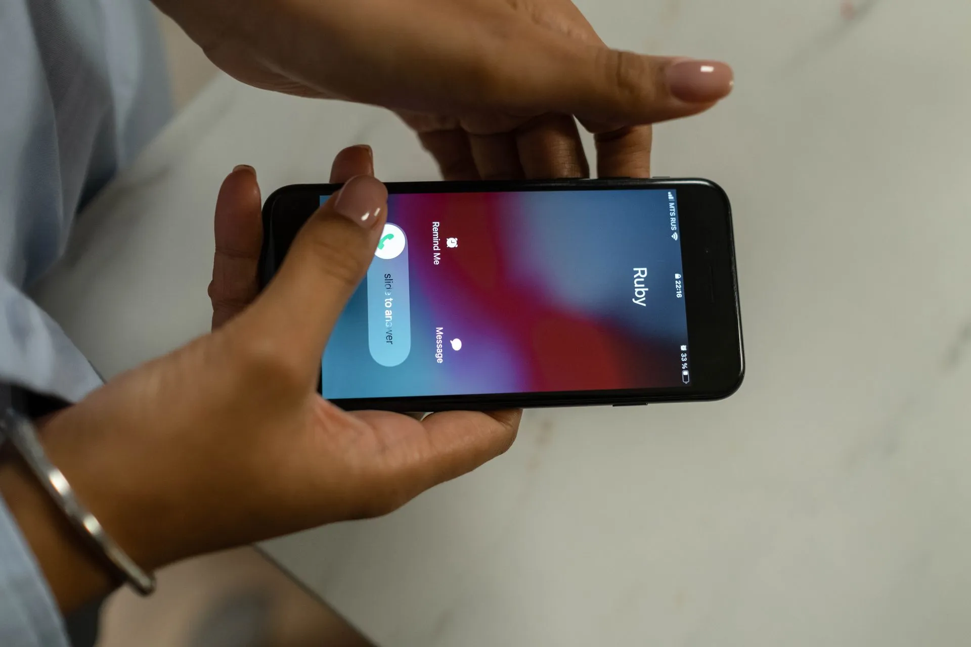 Close-up image of hands holding a smartphone receiving a call from Ruby on a marble surface, illustrating Astrana Health cyberattack involved calls spoofing its own phone number, 8-K