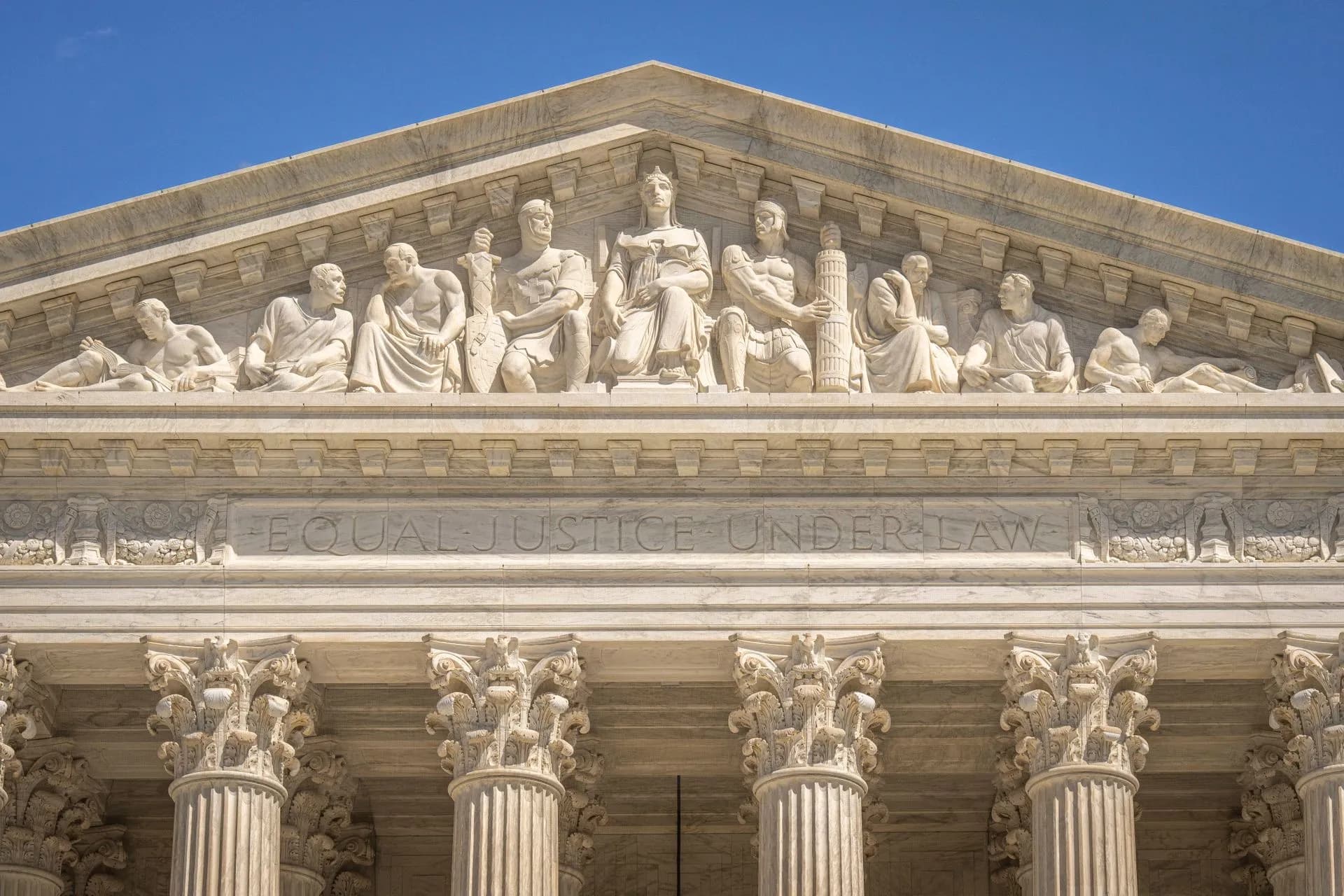 Detailed view of the Supreme Court Building's frontal frieze depicting historical figures and justices, illustrating Atlassian public sector cloud plan pulls DoD IL5 submission forward
