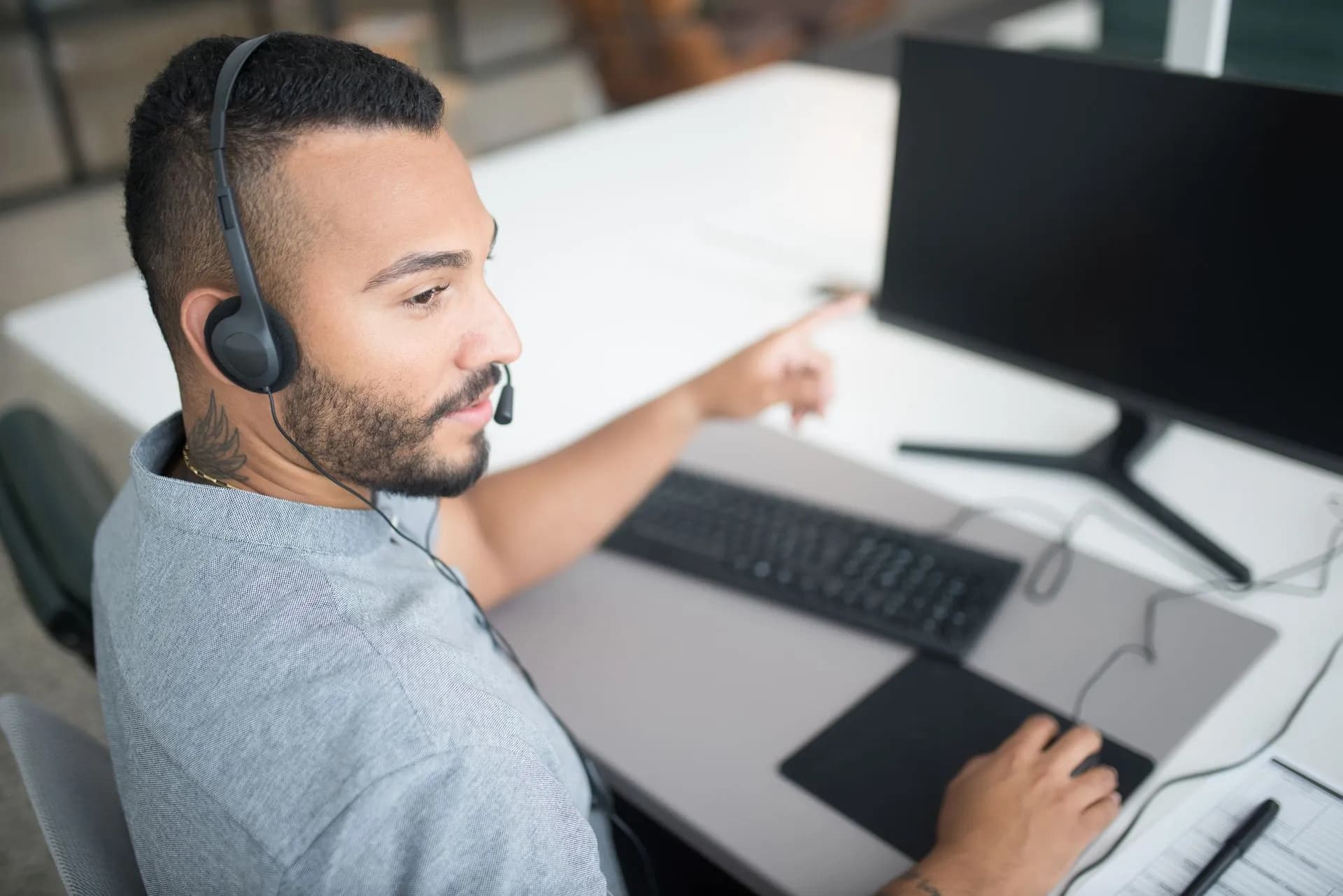 Customer service agent using a computer and headset within a modern office setting, illustrating Automation Anywhere to acquire Boost.ai from Nordic Capital to add customer-facing