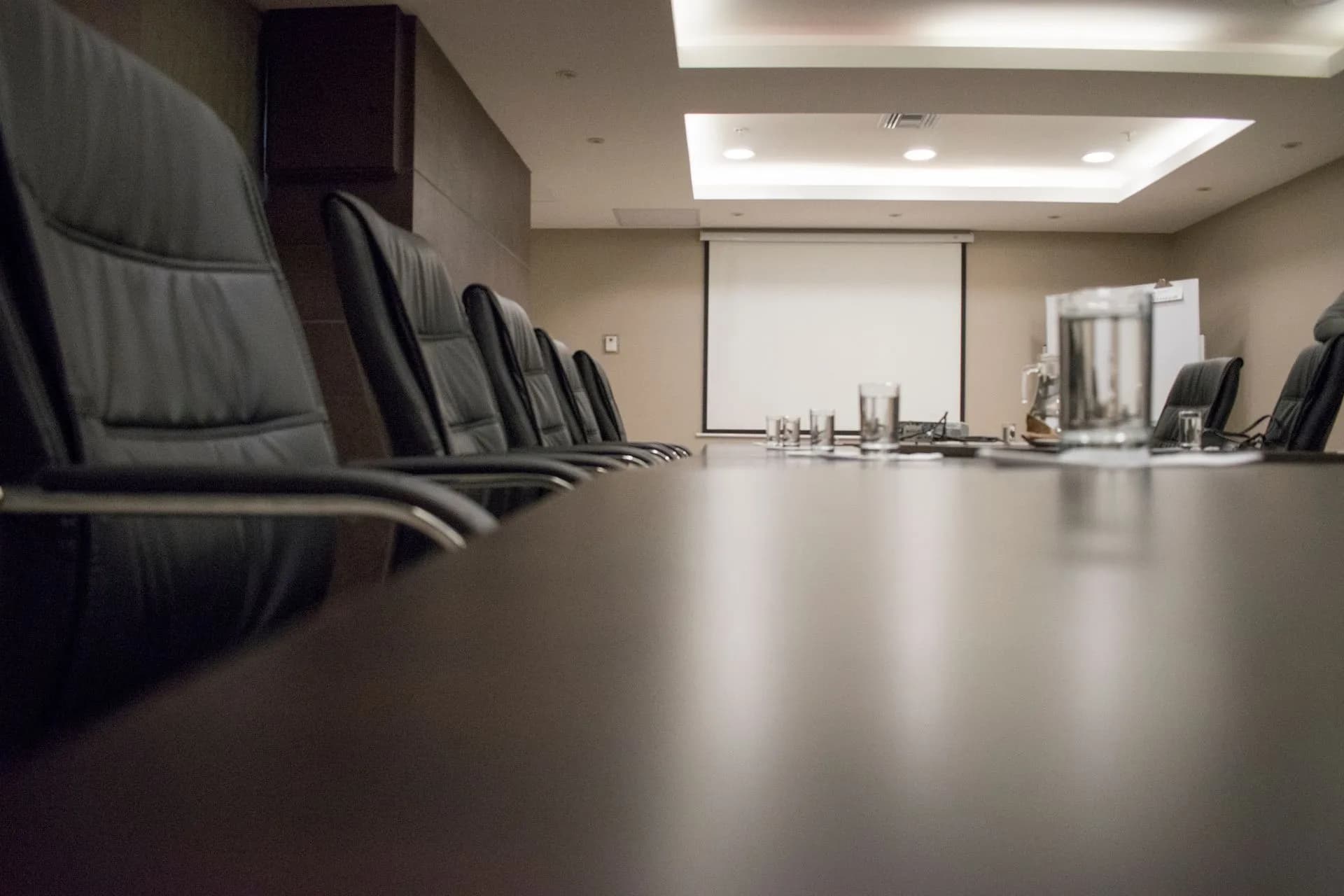 Empty conference room with black chairs, projector, and glasses on table. Ideal for business meetings, illustrating Automattic board replaced by Matt Mullenweg after failed attempt to