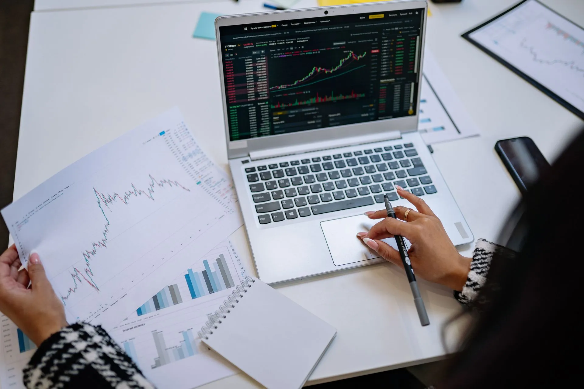 A detailed look at business analysis with a laptop displaying graphs and financial charts on a table, illustrating AWS Aurora PostgreSQL embeds DuckDB to query Iceberg and Parquet data