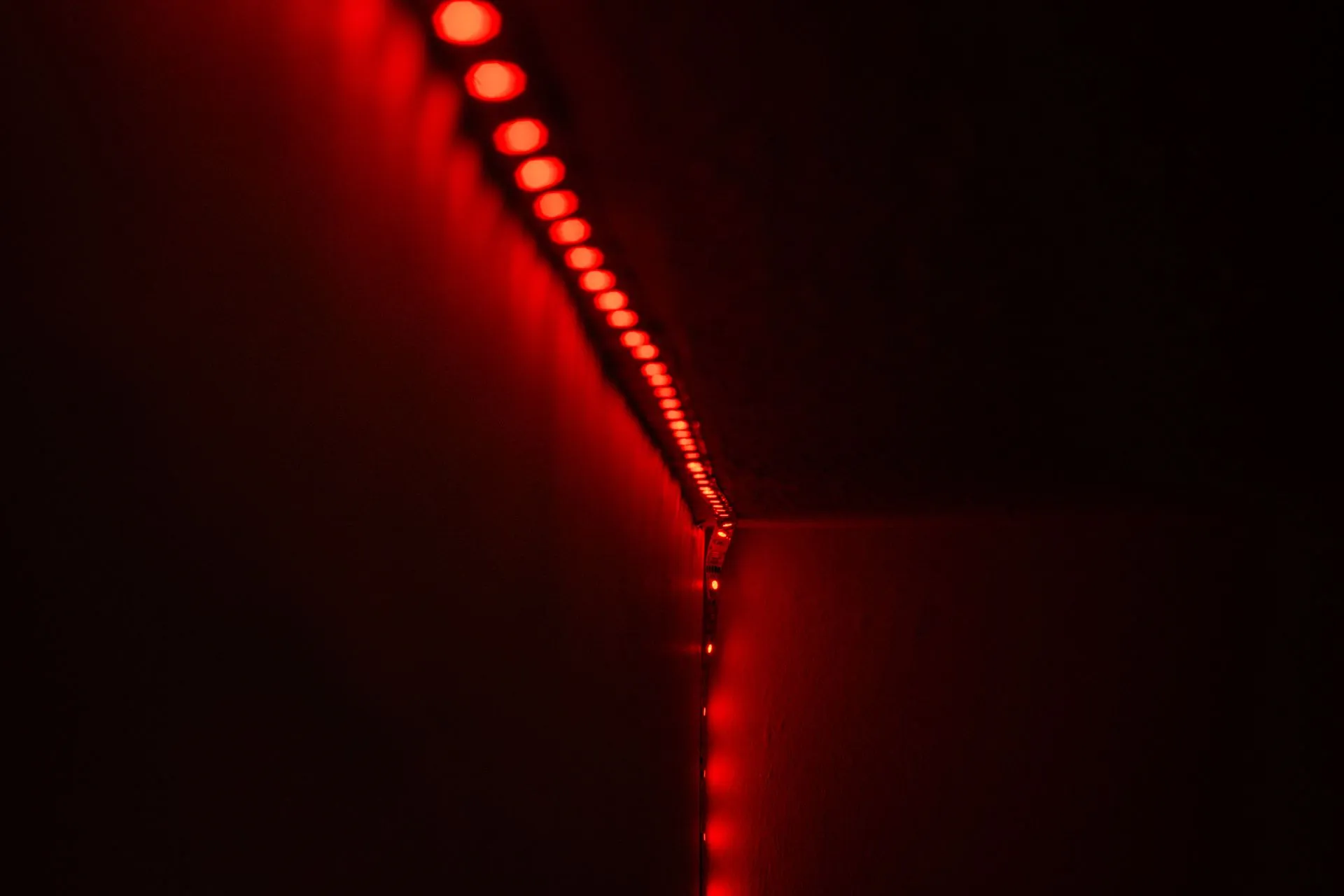 Close-up of red LED strip lights illuminating a dark room, creating a moody atmosphere, illustrating Sean Cairncross defends White House private-sector hacking program, urges security