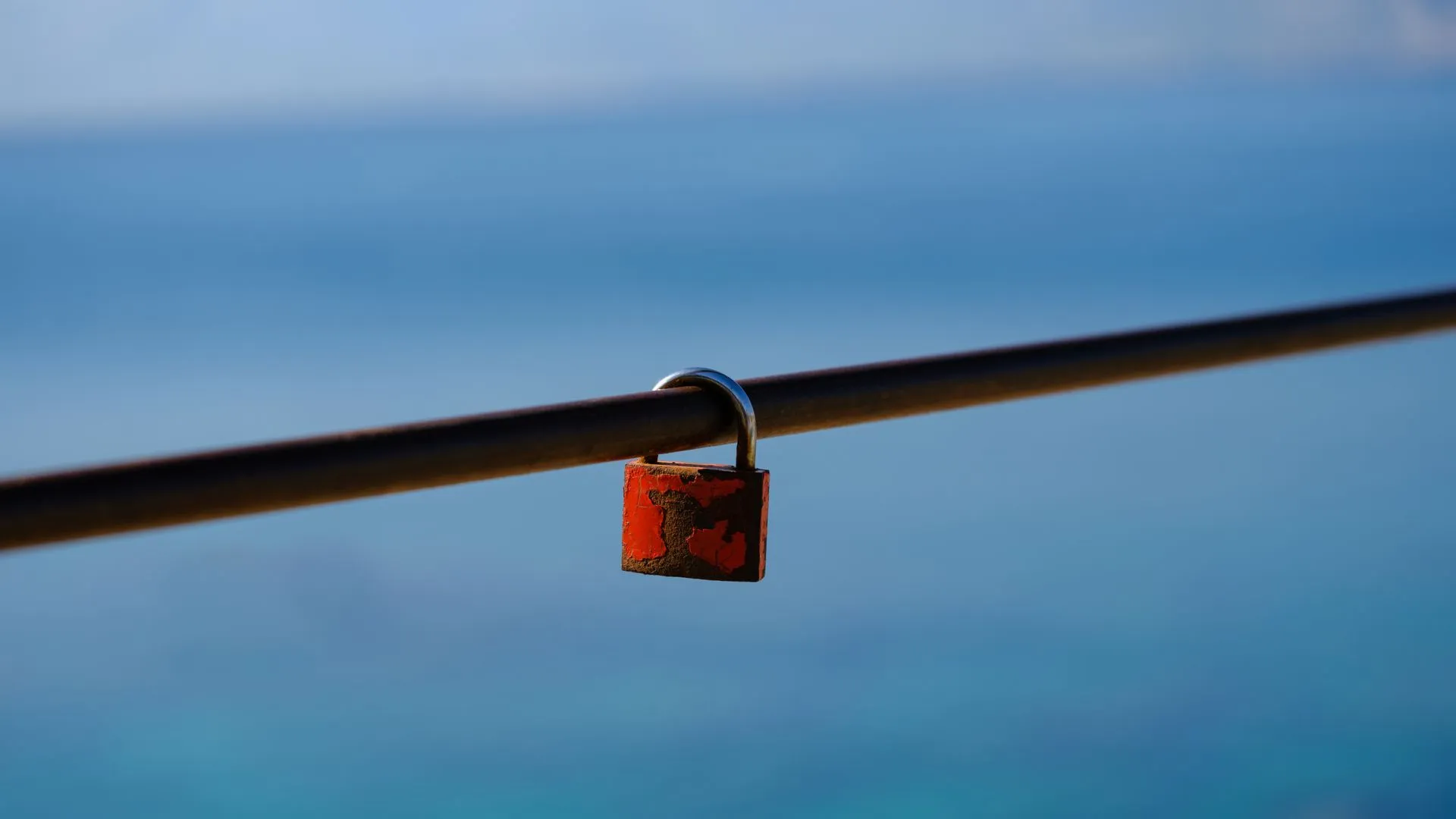 Old rusty padlock locked on a metal rail with a blurred blue sea background, illustrating Google says hijacked .gh, .sl and .as registries let attackers get HTTPS certificates for its