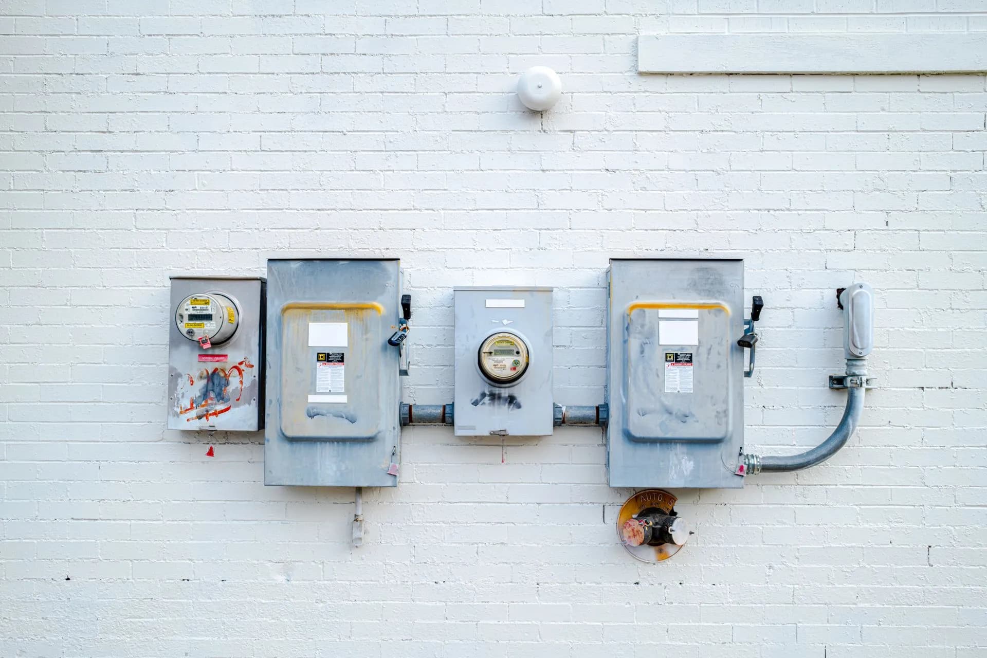 Electrical boxes and power meters mounted on a white brick wall, illustrating CenterPoint Energy data breach confirmed after hacker claims 7.49 million records
