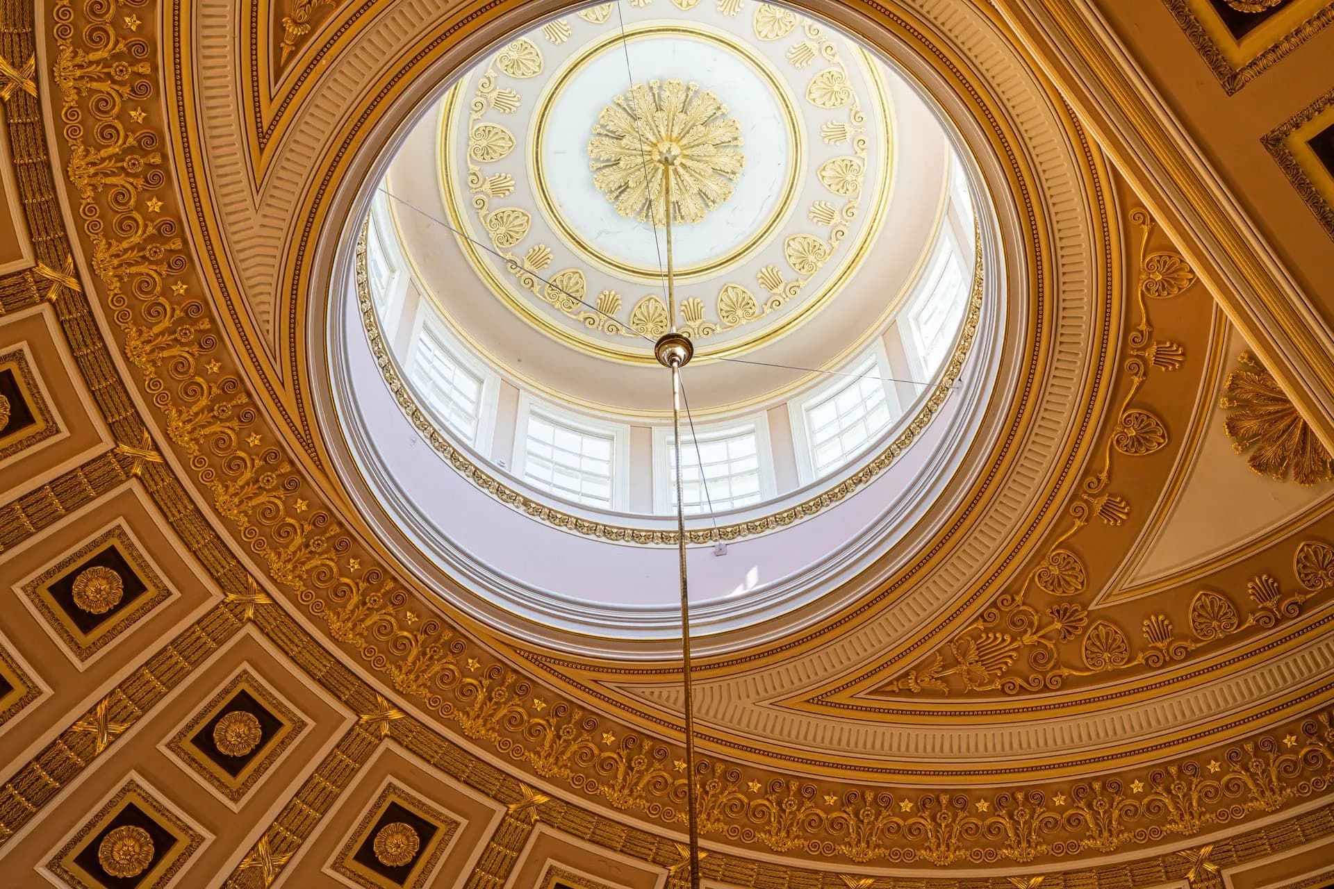 Captivating view of a domed ceiling with intricate golden patterns and sunlight from Washington, D.C, illustrating CFPB in flux after funding ruling and Senate vote