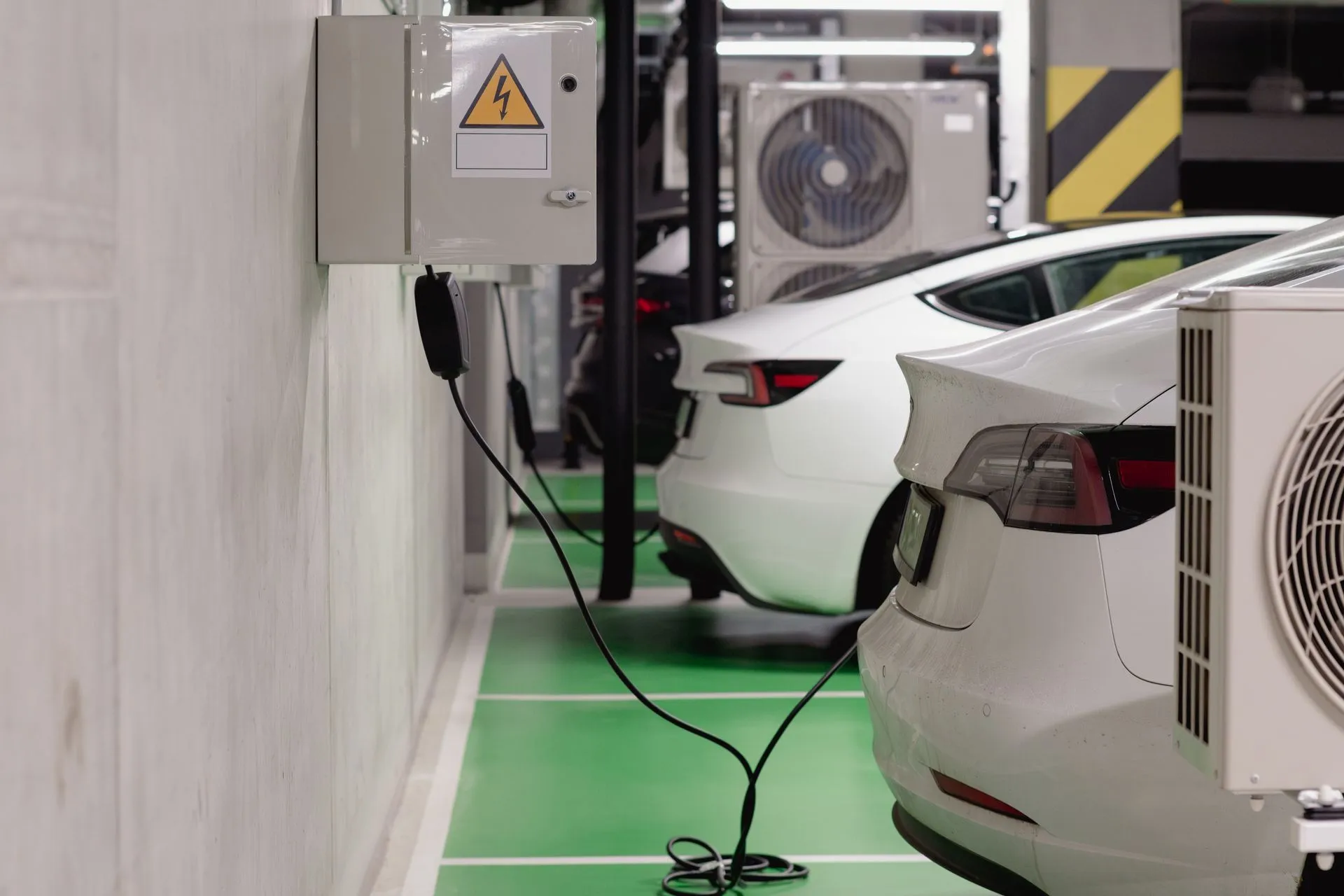 Electric vehicles charging at an indoor station in a modern underground garage, illustrating CISA advisories flag EV charger, door access and IoT cloud flaws rated up to 9.8