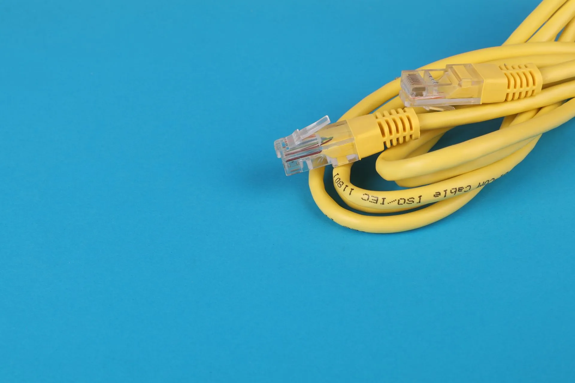 Close-up of a yellow Ethernet cable with connectors on a blue background, illustrating Cisco SD-WAN zero-day exploited to give attackers admin access