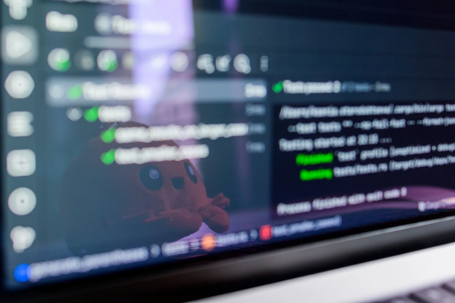 Close-up of a laptop screen displaying programming code with a cute plush toy reflecting, illustrating Cloudflare cf CLI covers 3,000+ API operations for AI agents as EmDash and vinext