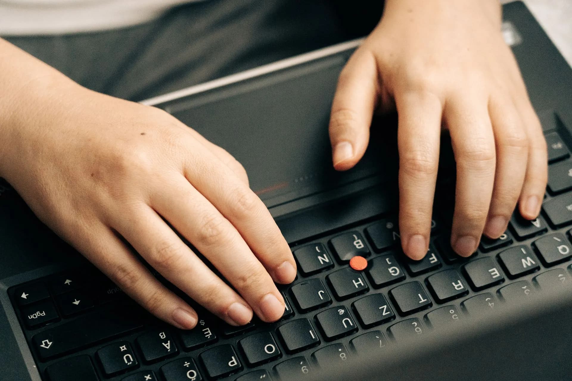 Close-up of hands typing on a black laptop's keyboard emphasizing productivity, illustrating Cloudflare plans a public certificate authority with post-quantum certs in early 2027