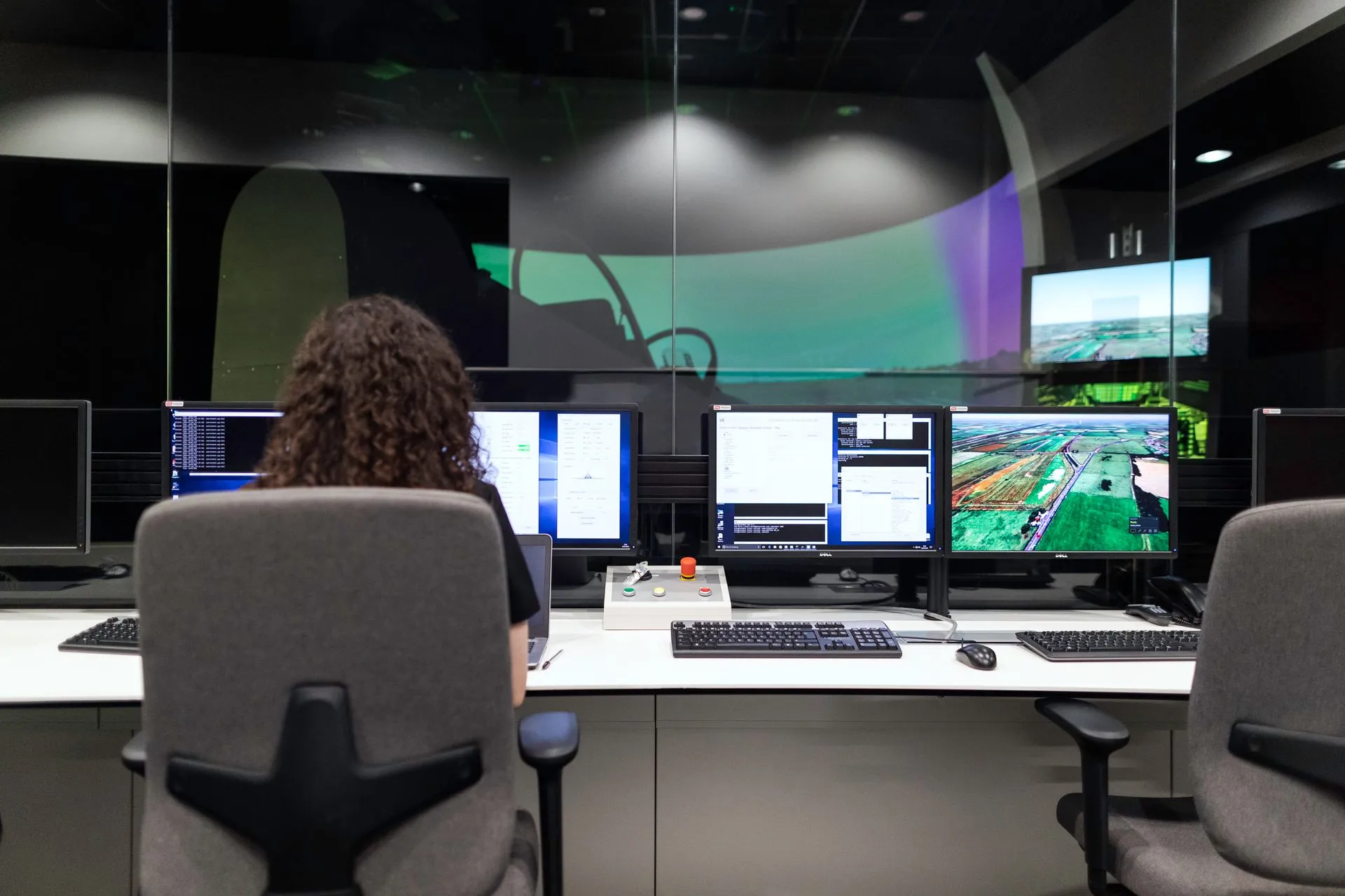 Female engineer managing multiple screens during a technology simulation in a control room, illustrating Cloudflare Threat Signals gives every account free AI parsing of public threat