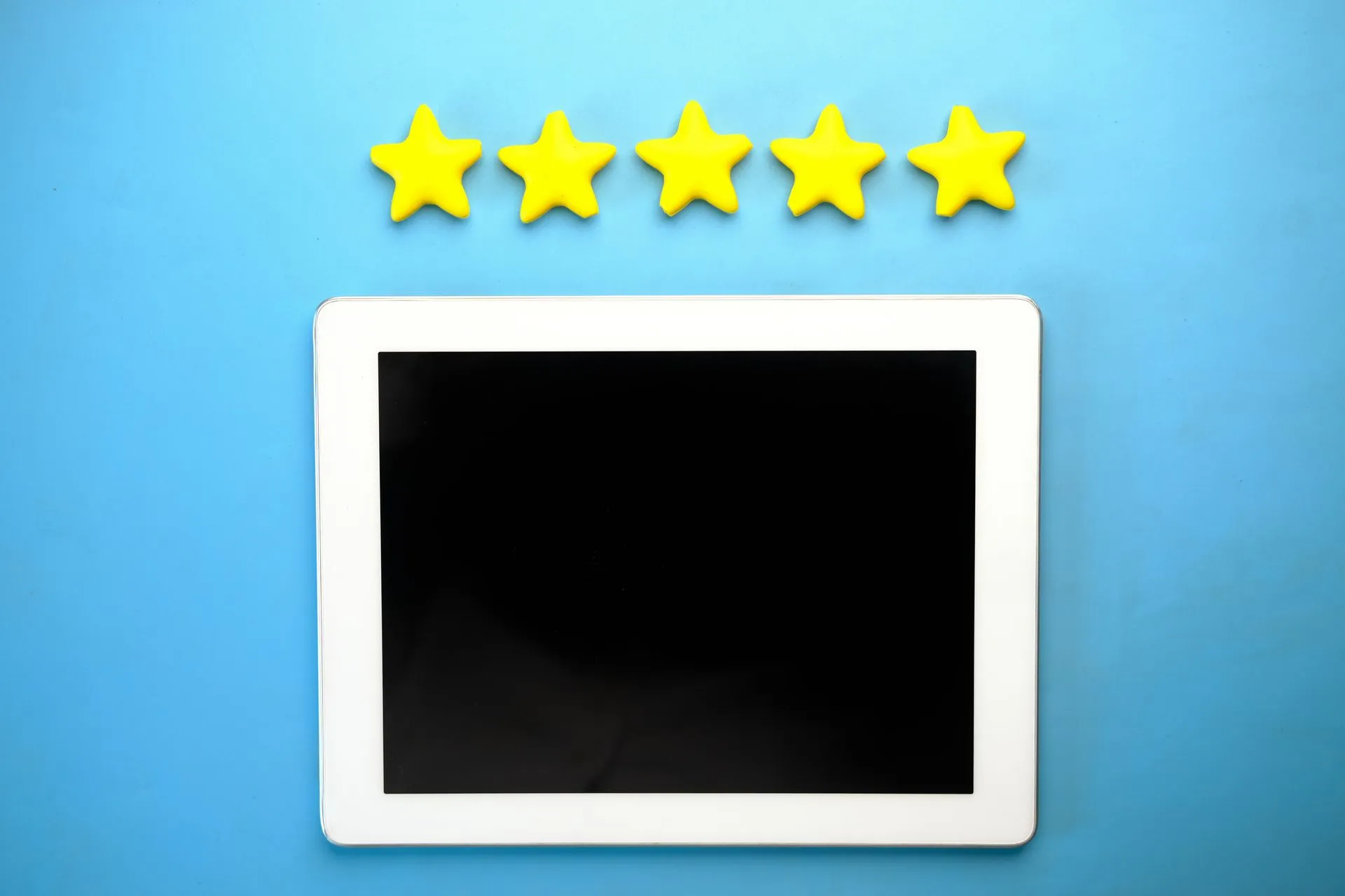 Tablet with five yellow stars on a blue background, ideal for rating concepts, illustrating CMA fake reviews probe of Just Eat, Autotrader and three others stays open six months on