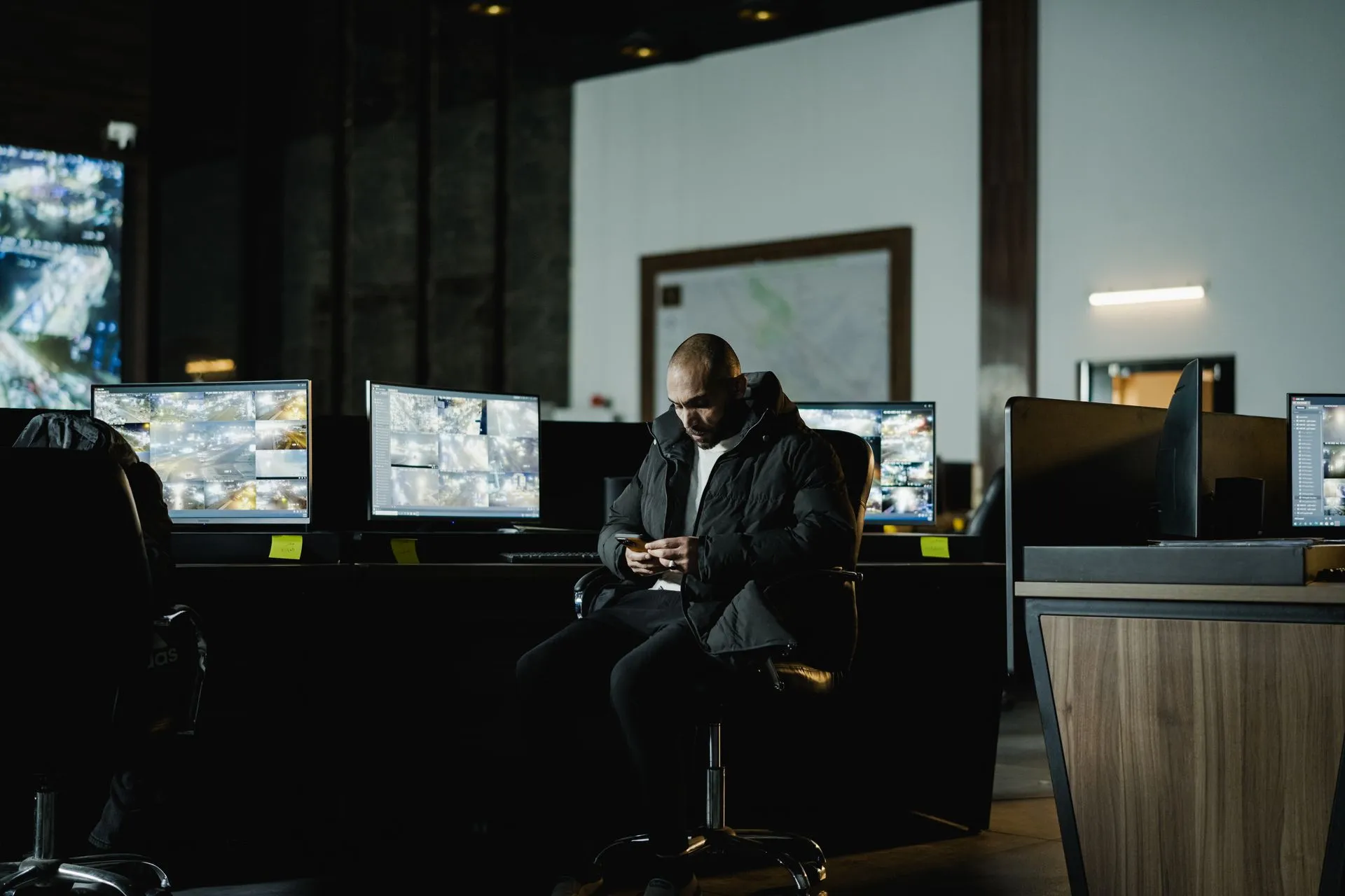 Security officer seated in a dimly lit control room, analyzing multiple surveillance screens, illustrating Cribl Detect SIEM launches with a claim of up to 50% lower cost than rival