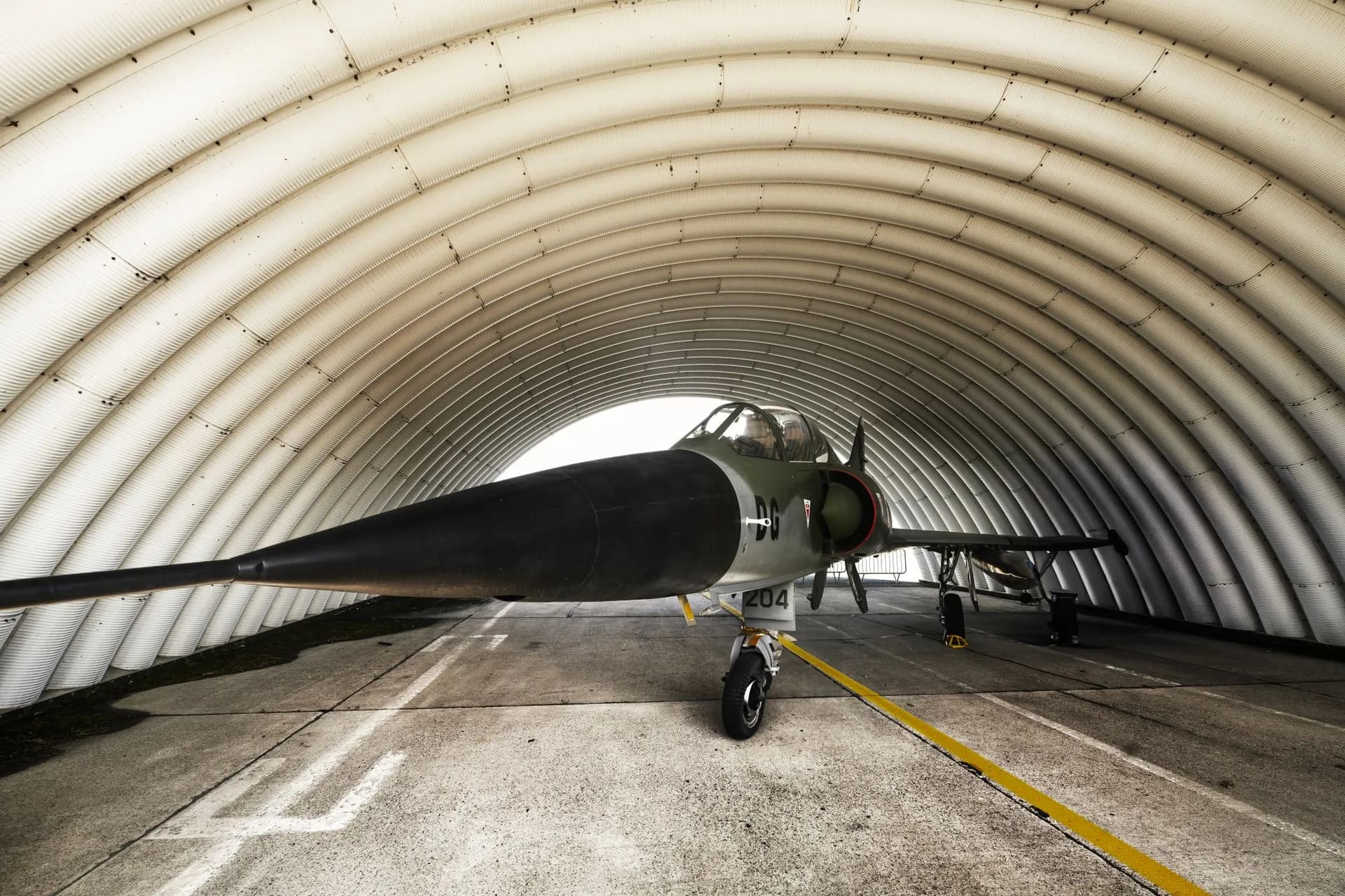 A fighter jet parked inside an arched military hangar, showcasing its sleek design, illustrating Mach Industries' $3.7 billion valuation caps a record run for defense tech funding
