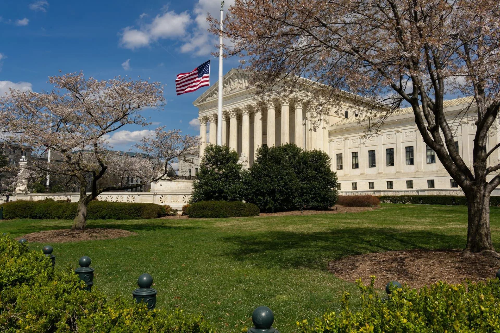 A view of a neoclassical government building with an American flag and cherry blossoms in Washington, DC, illustrating Delaware's plan for AI-run companies runs into rogue agent