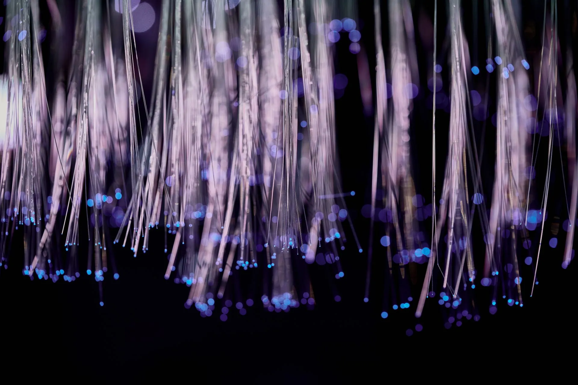 Close-up of glowing fiber optic lights with a purple and blue bokeh effect, illustrating Deutsche Telekom Cloudflare deal