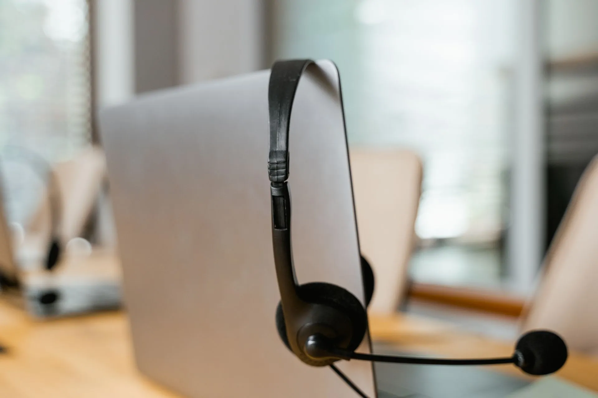 A headset hanging on a computer in a modern office setting for customer support, illustrating ElevenLabs valuation doubles to $22 billion as voice agents move into customer service