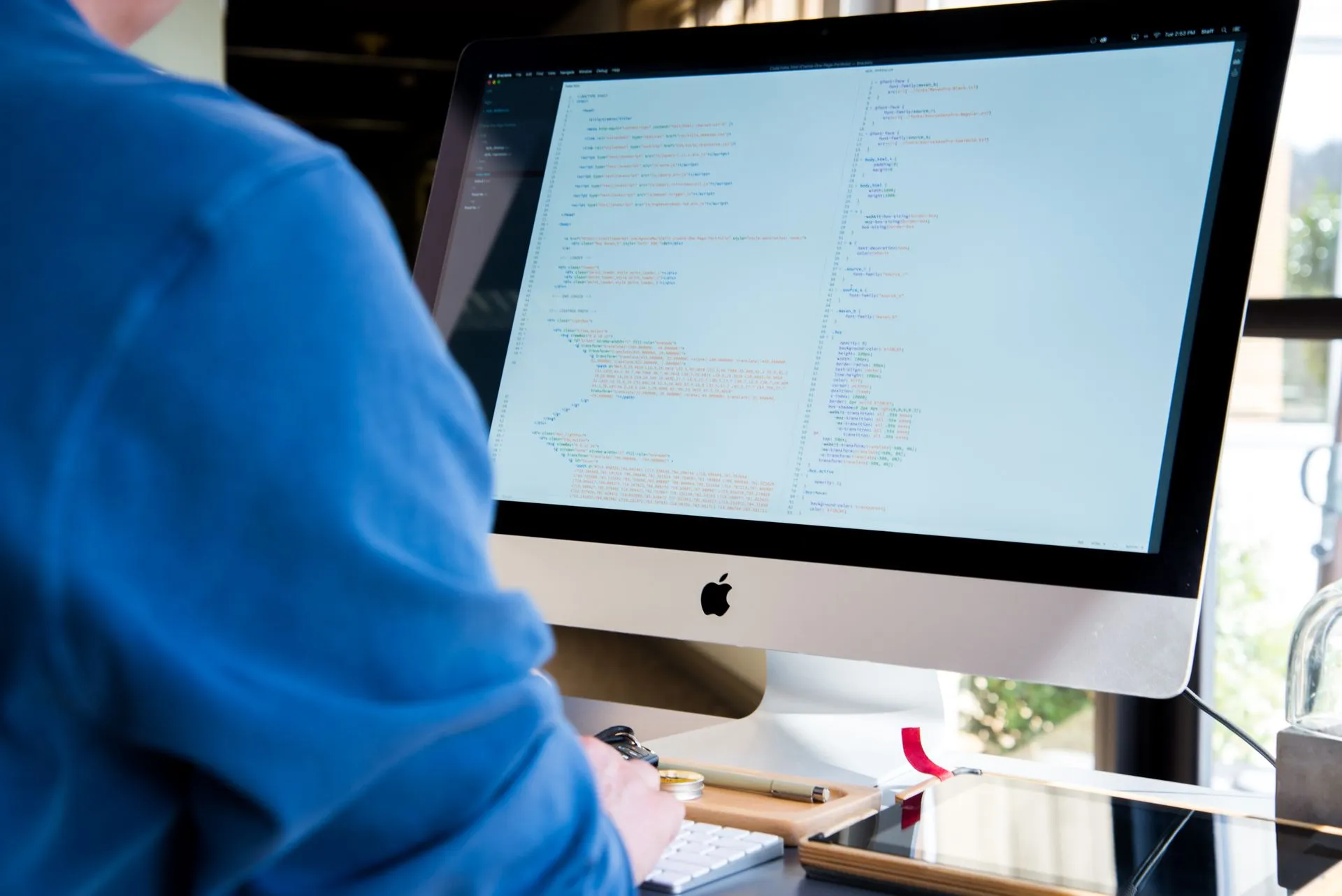 A programmer in a blue shirt coding on an iMac. Perfect for technology or work-related themes, illustrating Cognition, Temporal and Factory rounds show what enterprises will pay for in