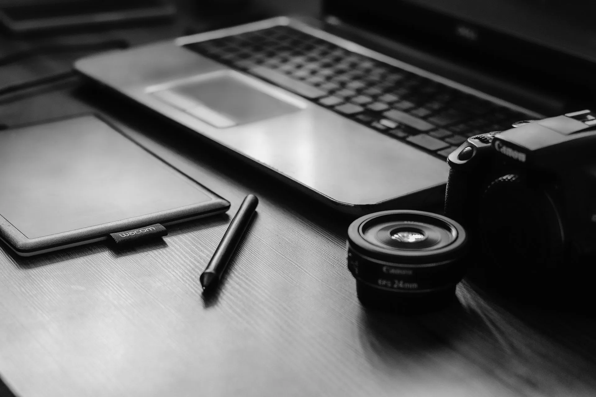 A monochromatic workspace with a camera, laptop, lens, and tablet, ideal for photographers, illustrating Fake ChatGPT 'Plus 5.6' bot in Google ads led to webcam-spying malware