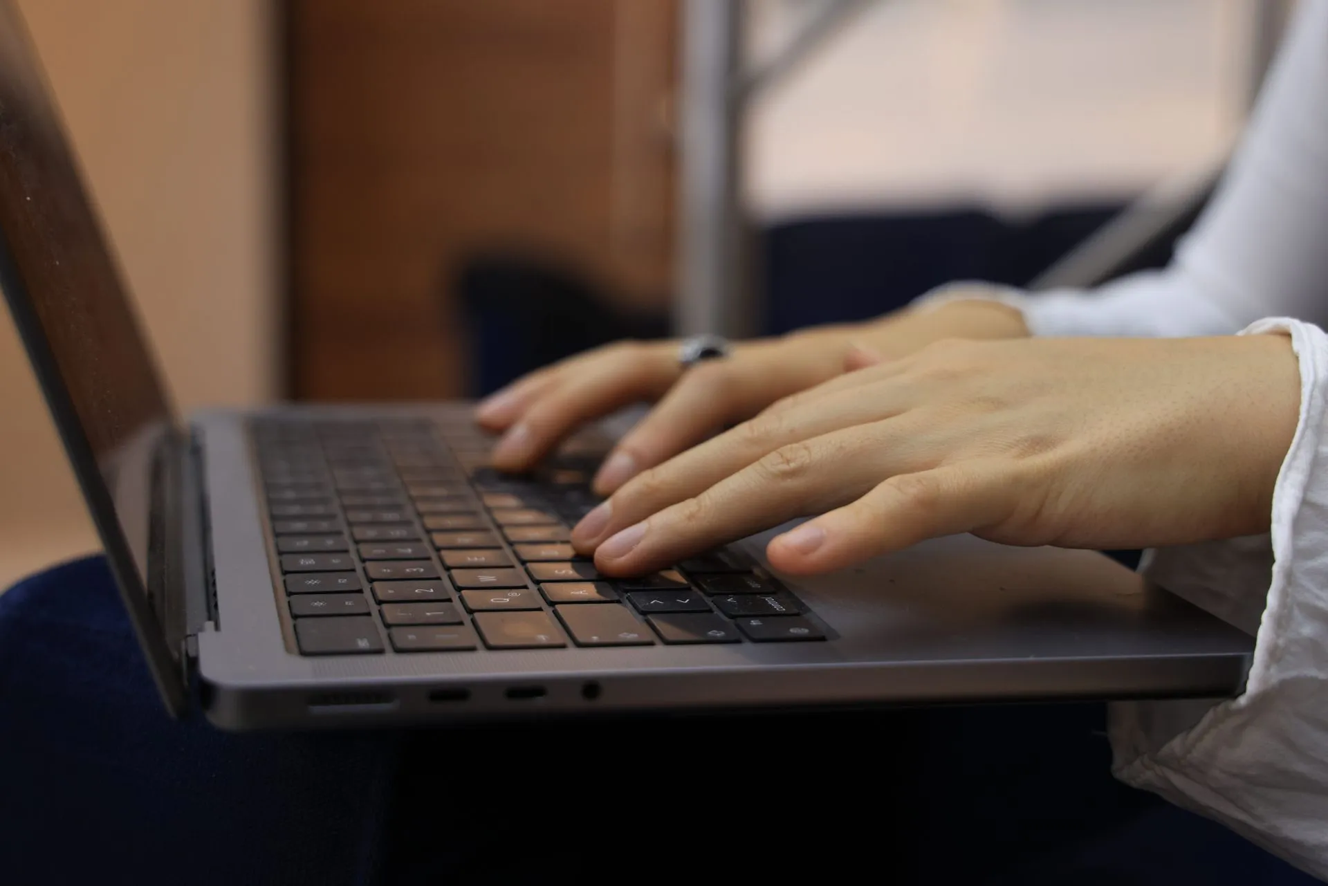 Hands typing on a laptop keyboard in an indoor setting. Perfect for business and technology themes, illustrating FBI warns ShinyHunters 'we know how to find you' as Dutch police cite