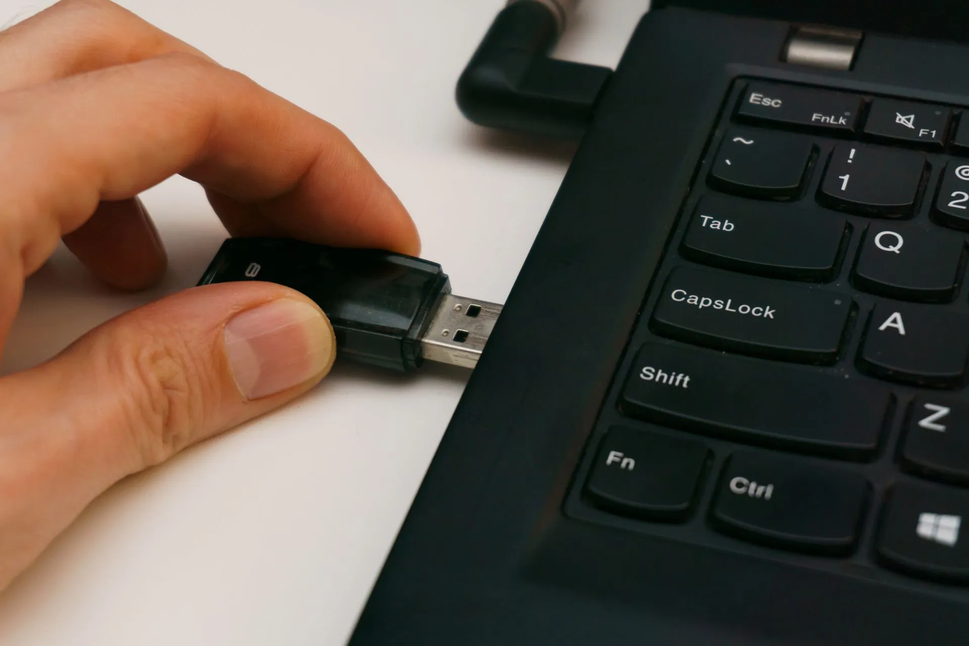 Close-up of a USB pen drive being inserted into a laptop USB port on a white surface, illustrating Fed inspector general