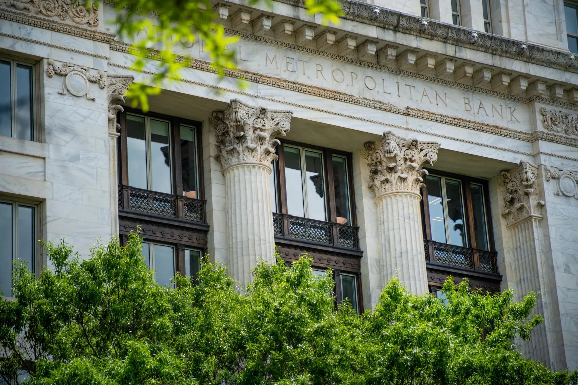 Close-up of the neoclassical columns and facade of Metropolitan Bank surrounded by greenery, illustrating Fed cuts bank supervision to 5 regions as Stripe and Ramp push for direct Fed
