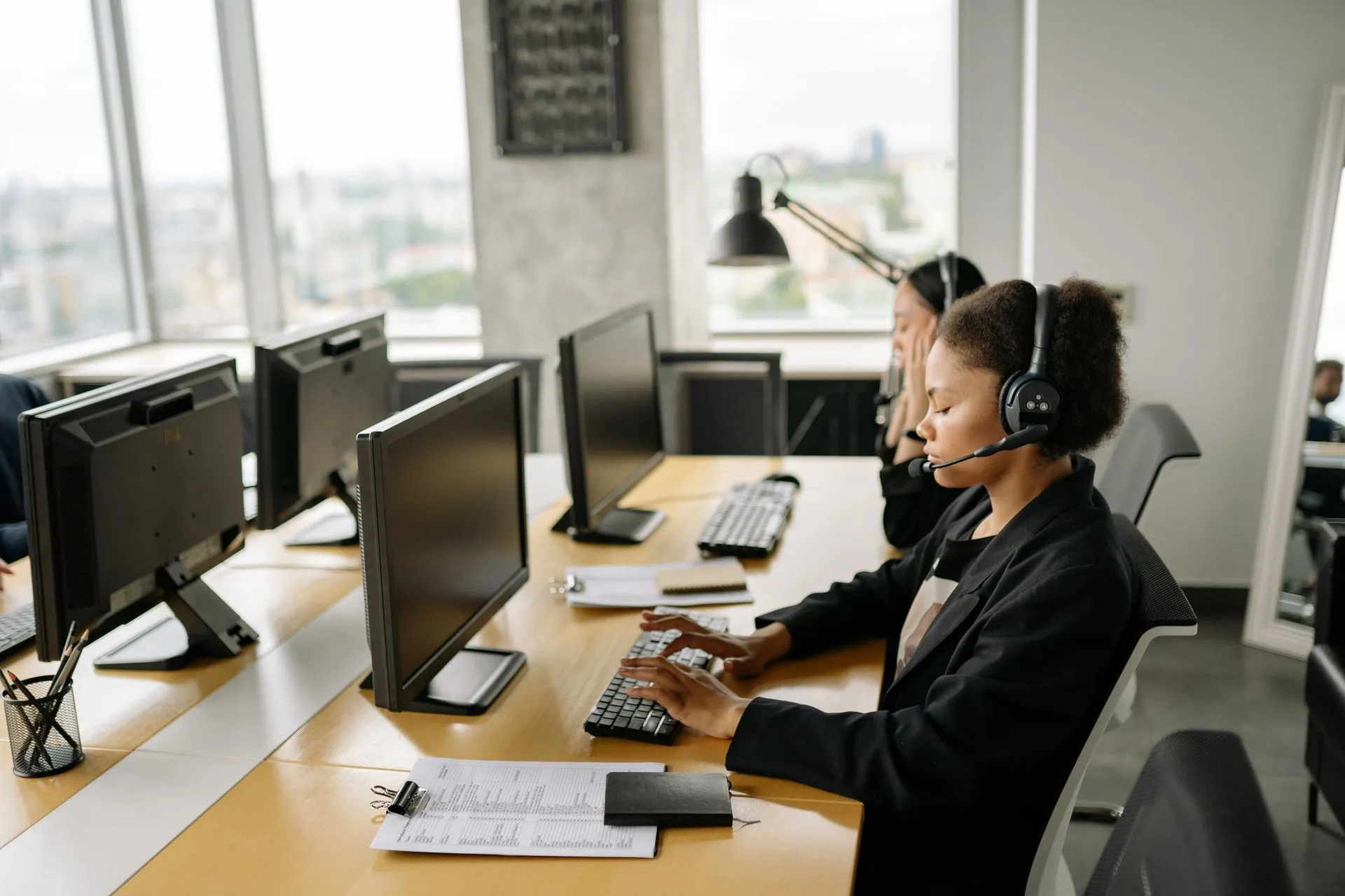 Customer support agents working at a call center with computers and headsets, focusing on tasks, illustrating Finastra launches AI repair recommendations to fix failed bank payments