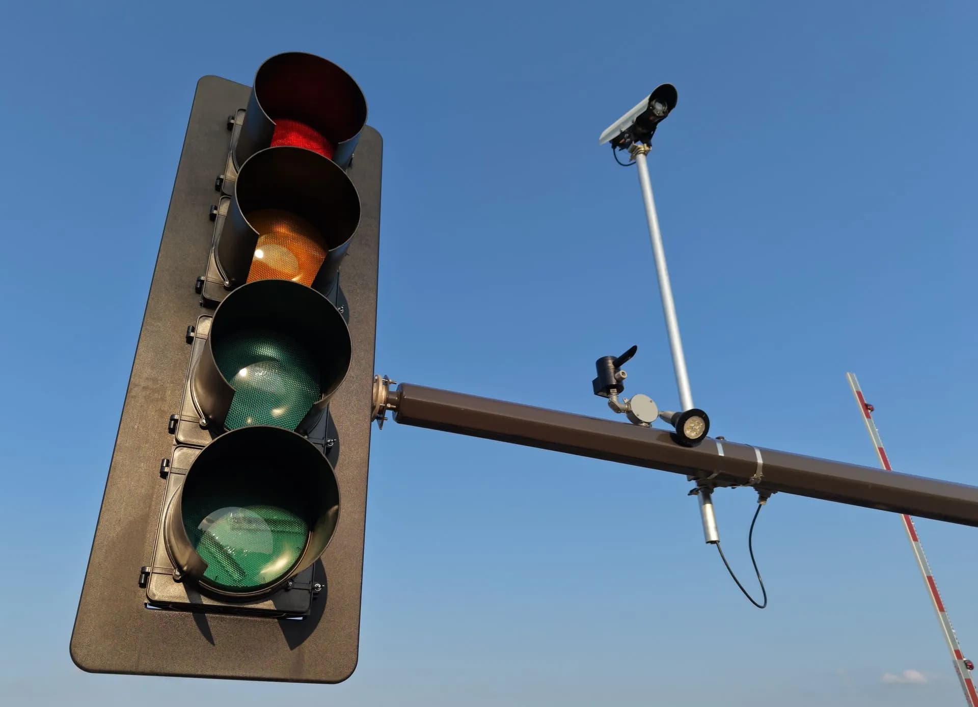 Urban scene with a traffic light and CCTV camera against a clear blue sky, illustrating Flock Safety faces a judge's 'mass surveillance' ruling and new bills from both parties
