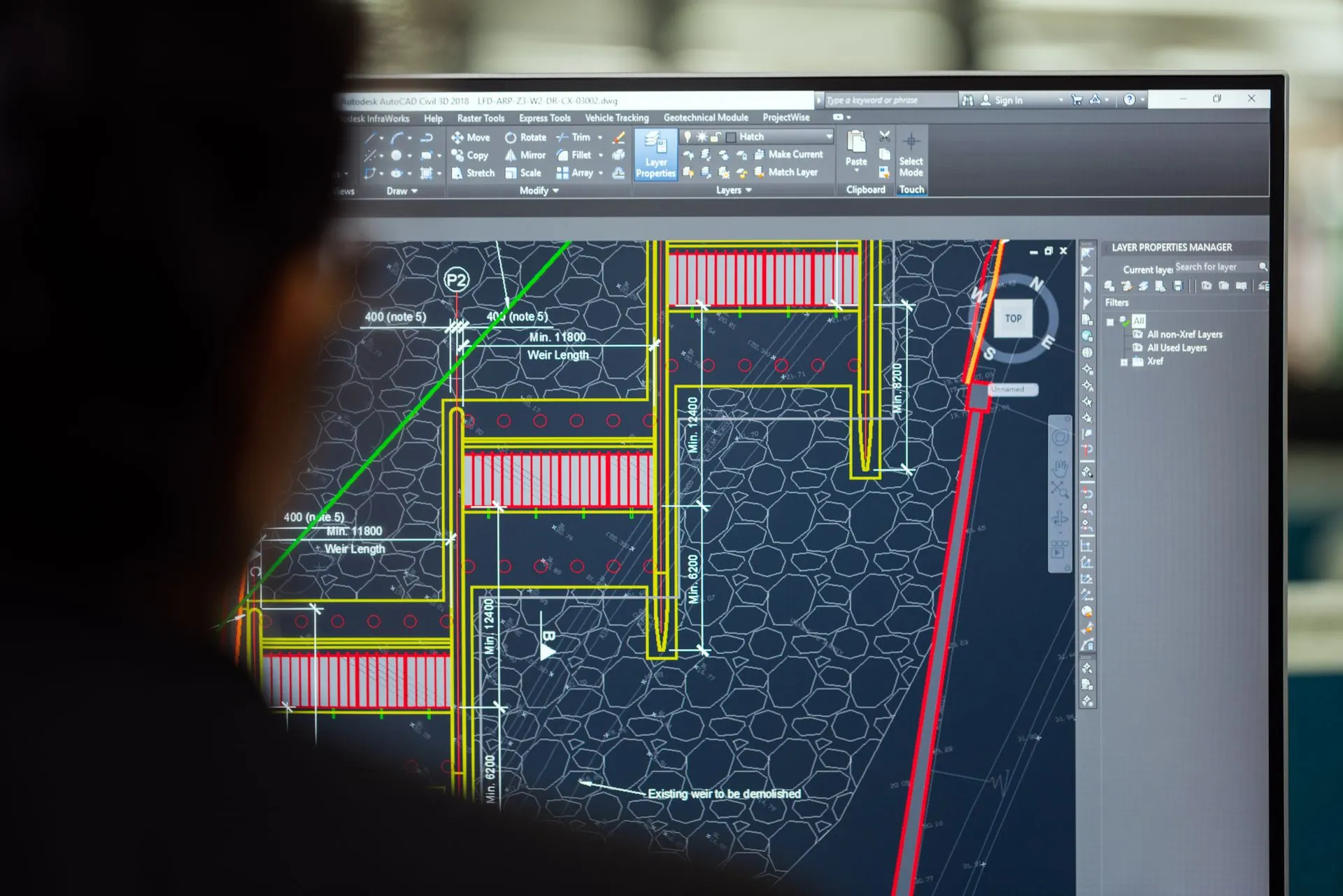 A civil engineer working on a weir design using CAD software on a computer screen in an office setting, illustrating Flow Engineering raises $50M at a $750M valuation to bring AI
