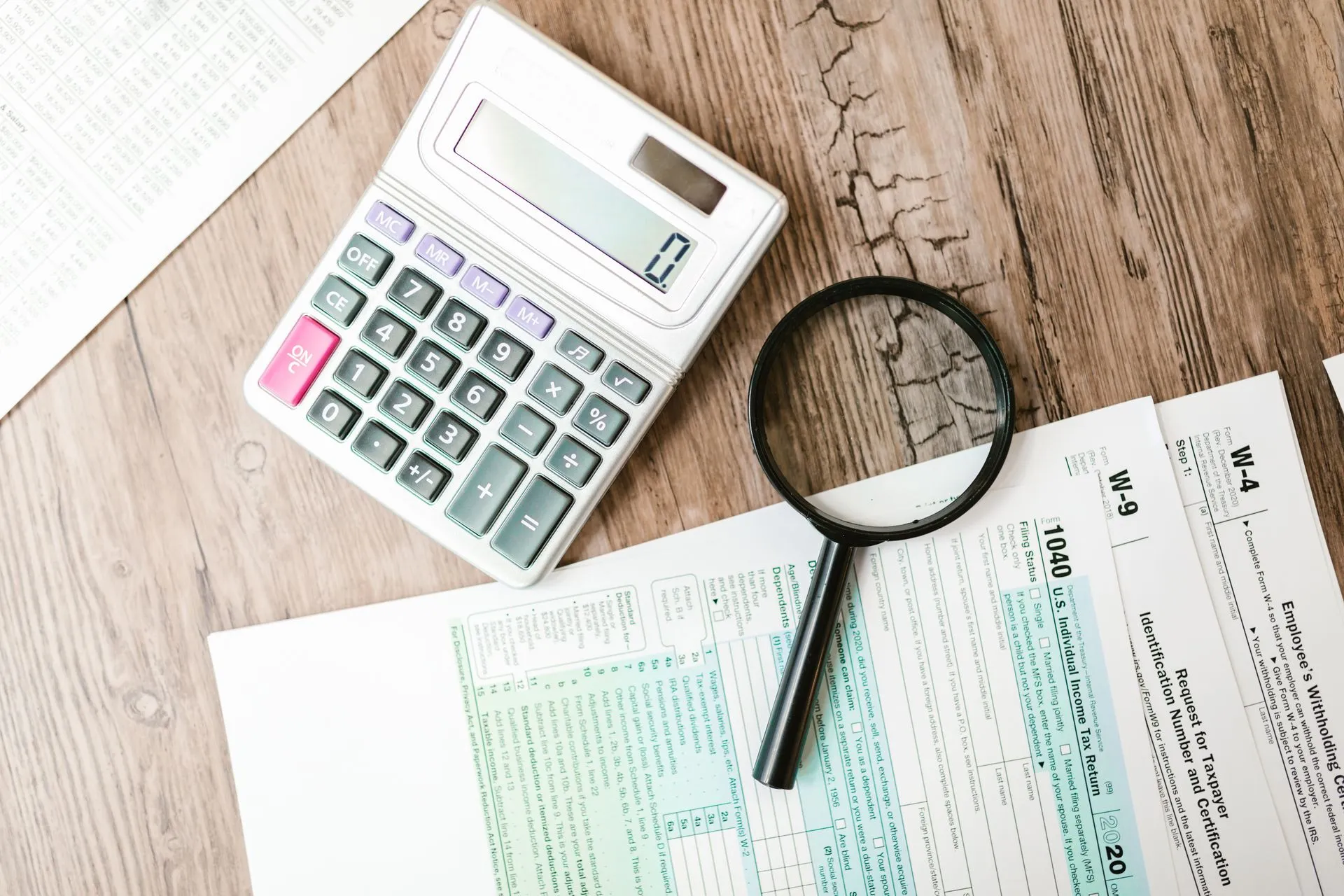 Tax forms laid out with a calculator and magnifying glass on a wooden surface, perfect for finance themes, illustrating French tax data breach went unnoticed for 7 weeks, until the