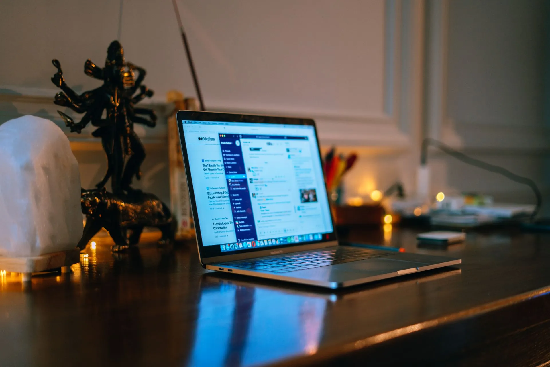A cozy home office setup with a laptop on a wooden desk surrounded by warm lighting and decor, illustrating Google Cloud launches Gemini Agent to run enterprise work across Microsoft