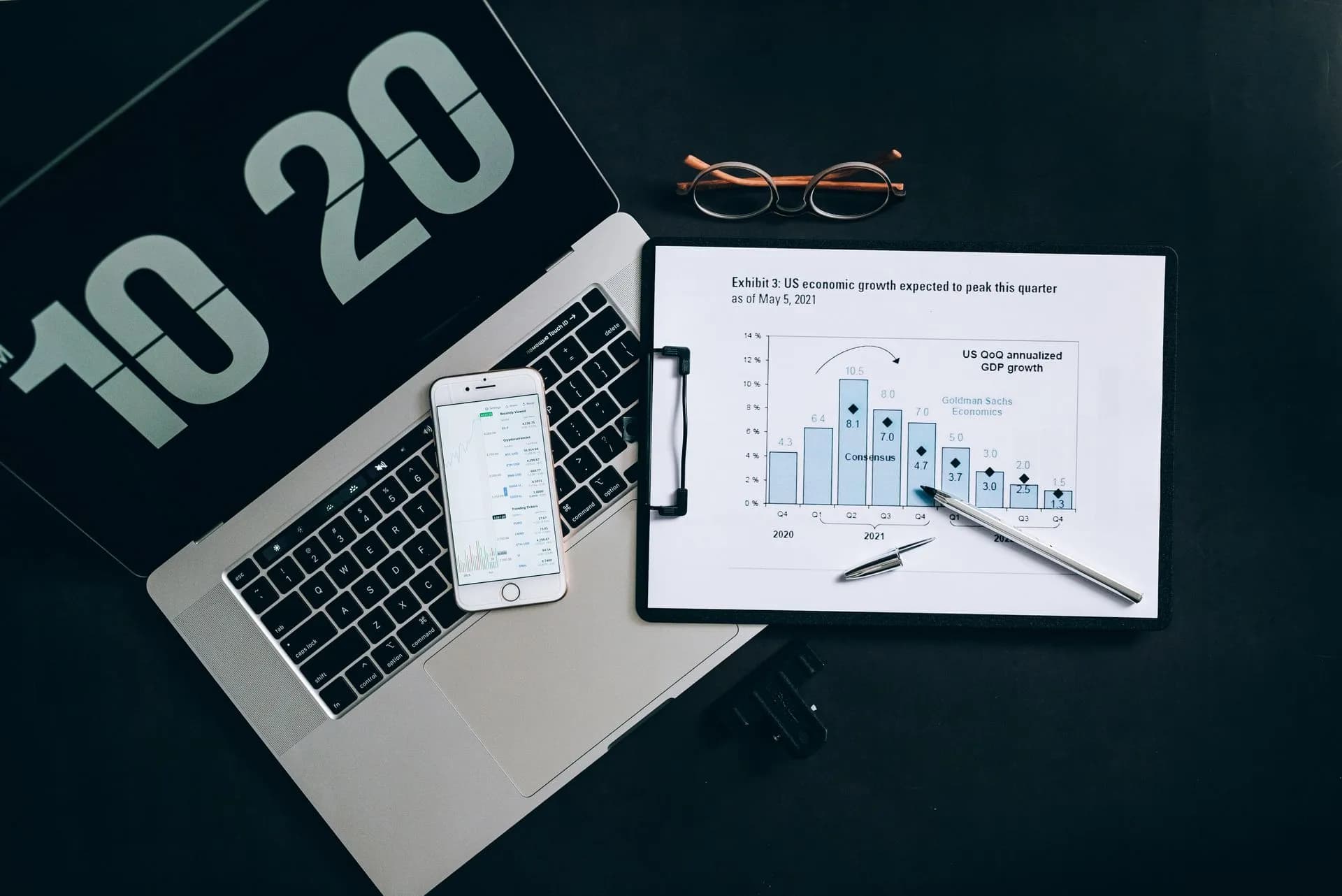 Top view of financial analysis tools on a desk including a laptop, smartphone, and graphs, illustrating Google Cloud Modernize bundles AI migration tools as Agentic Quick Estimator