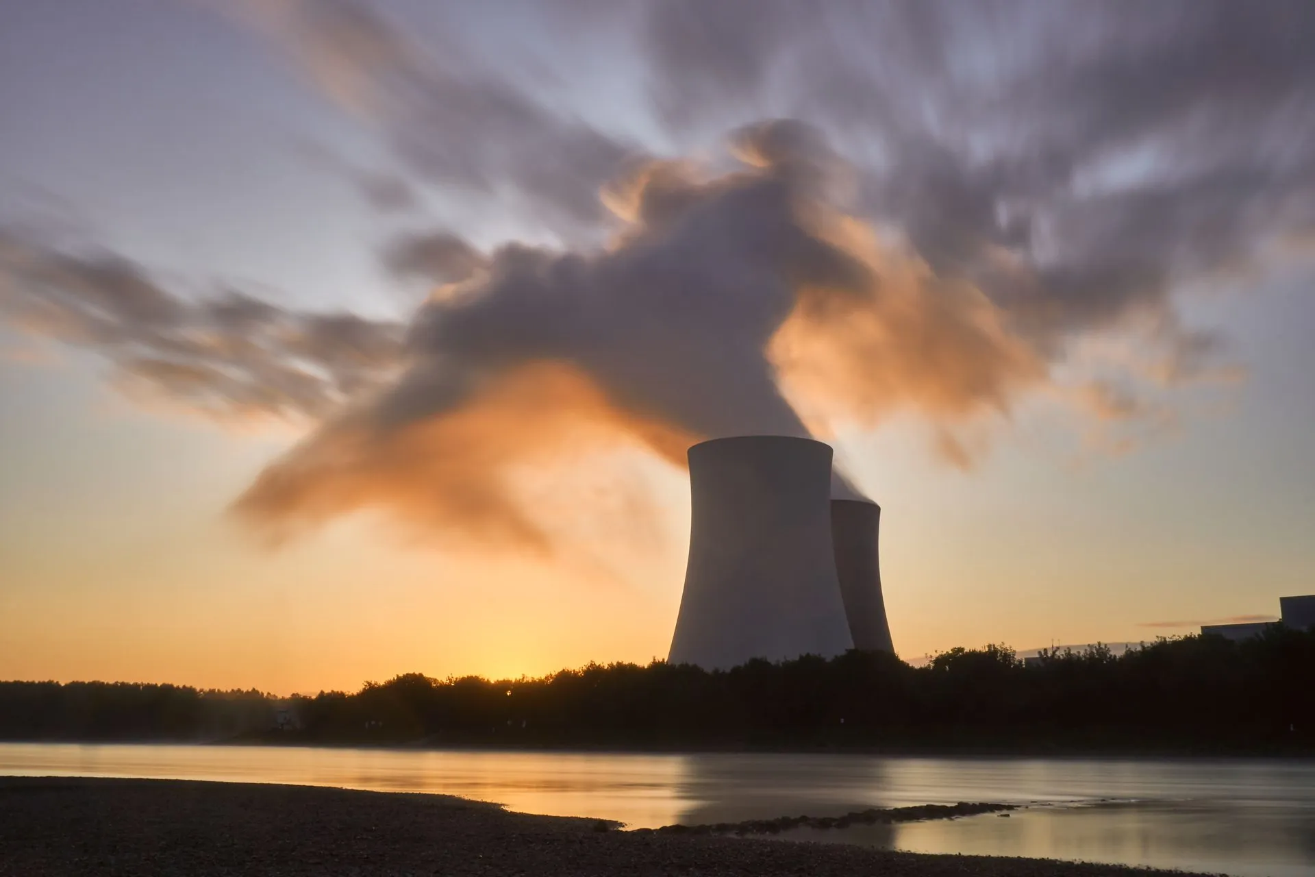 Dramatic image of a nuclear power plant at sunrise with steam rising into a colorful sky, illustrating Google signs for 890 MW of new nuclear power from Constellation plus 2,700 MW
