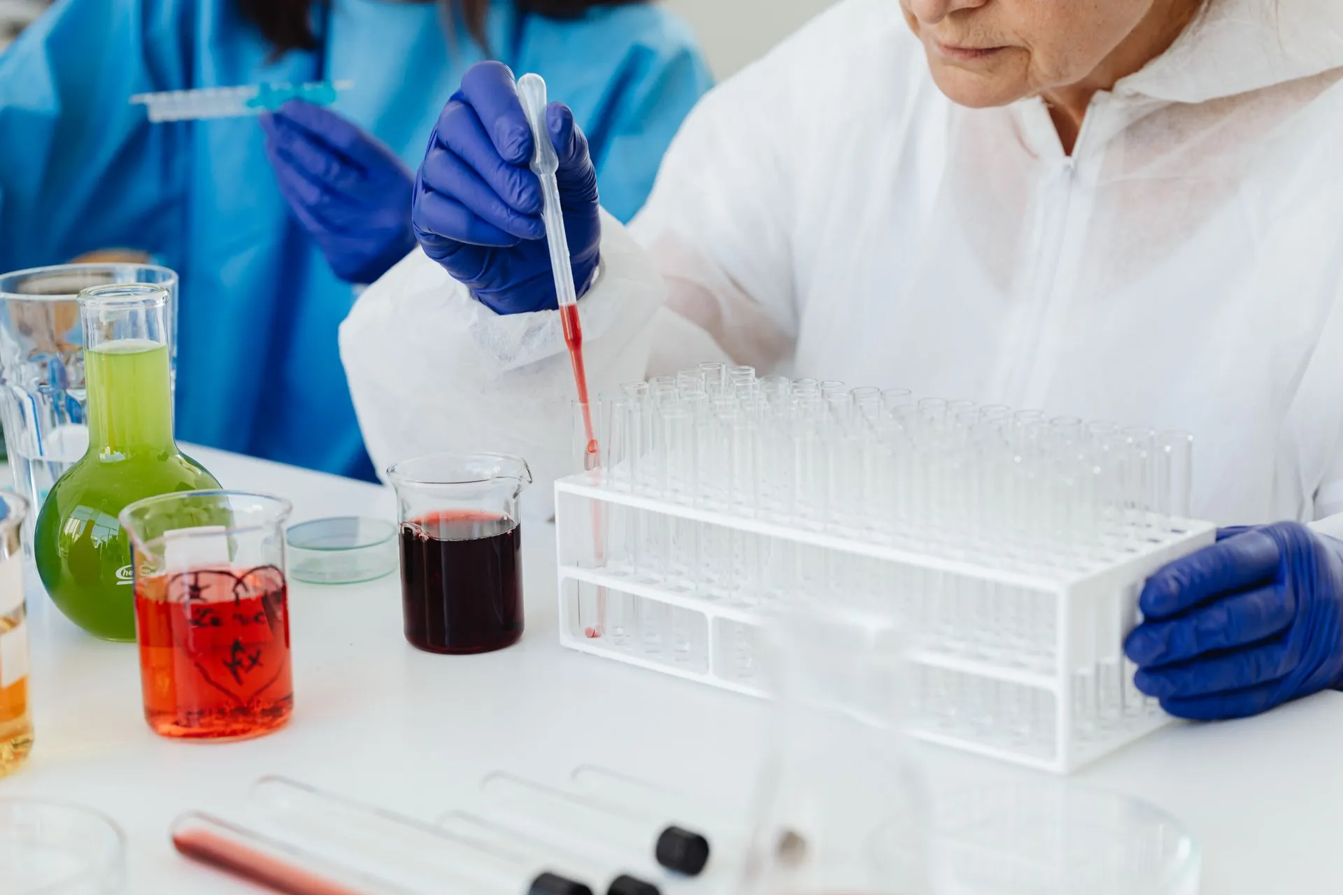 Female scientist in lab coat using pipette on test tubes, focusing on colorful chemical analysis, illustrating Google DeepMind unveils SynthID Bio to watermark AI-designed proteins