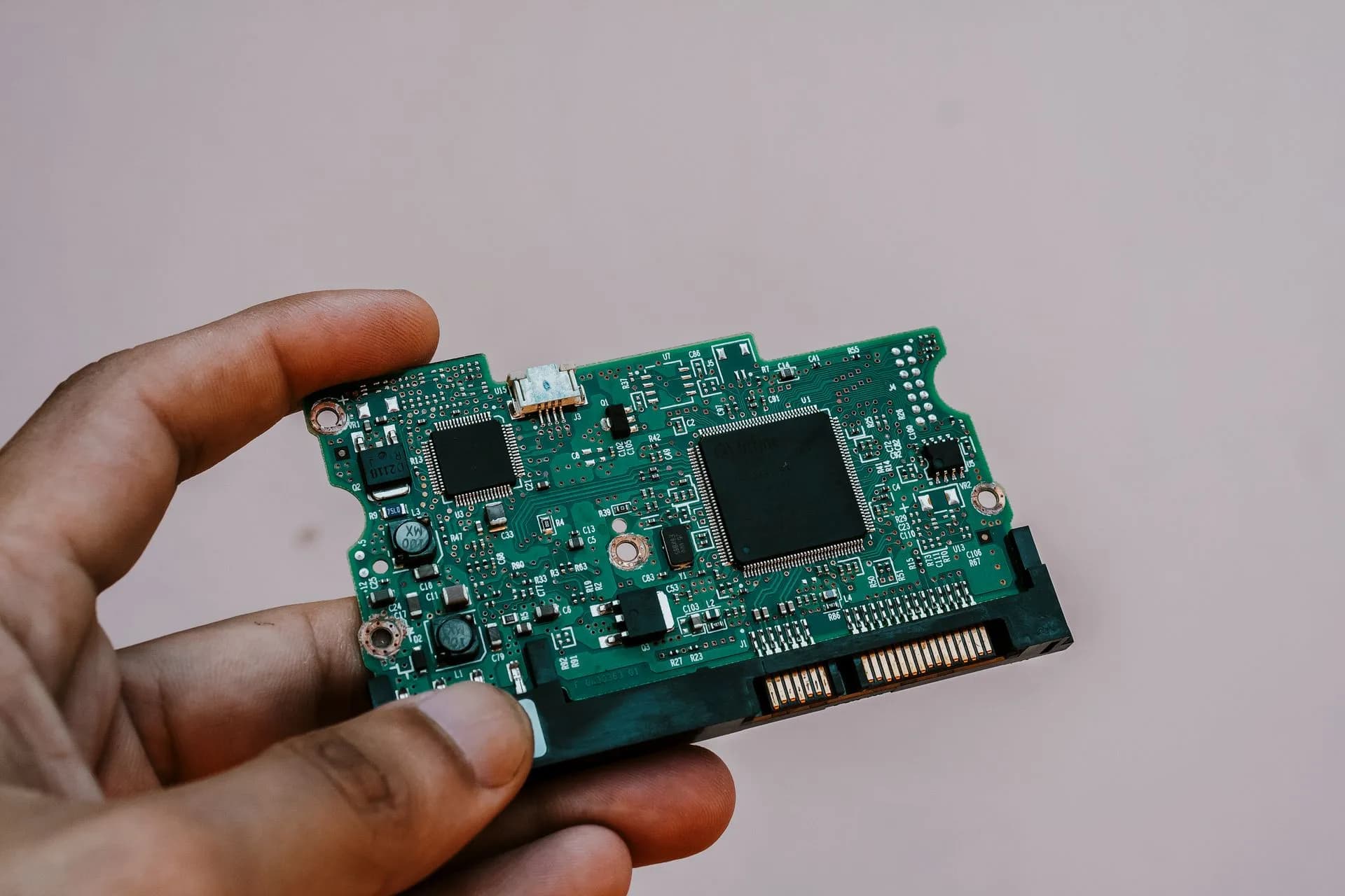 Close-up image of a hand holding a circuit board from a hard drive, showcasing electronic technology, illustrating Google's Gemini 4 Argon goes to vetted cyber defenders first, without