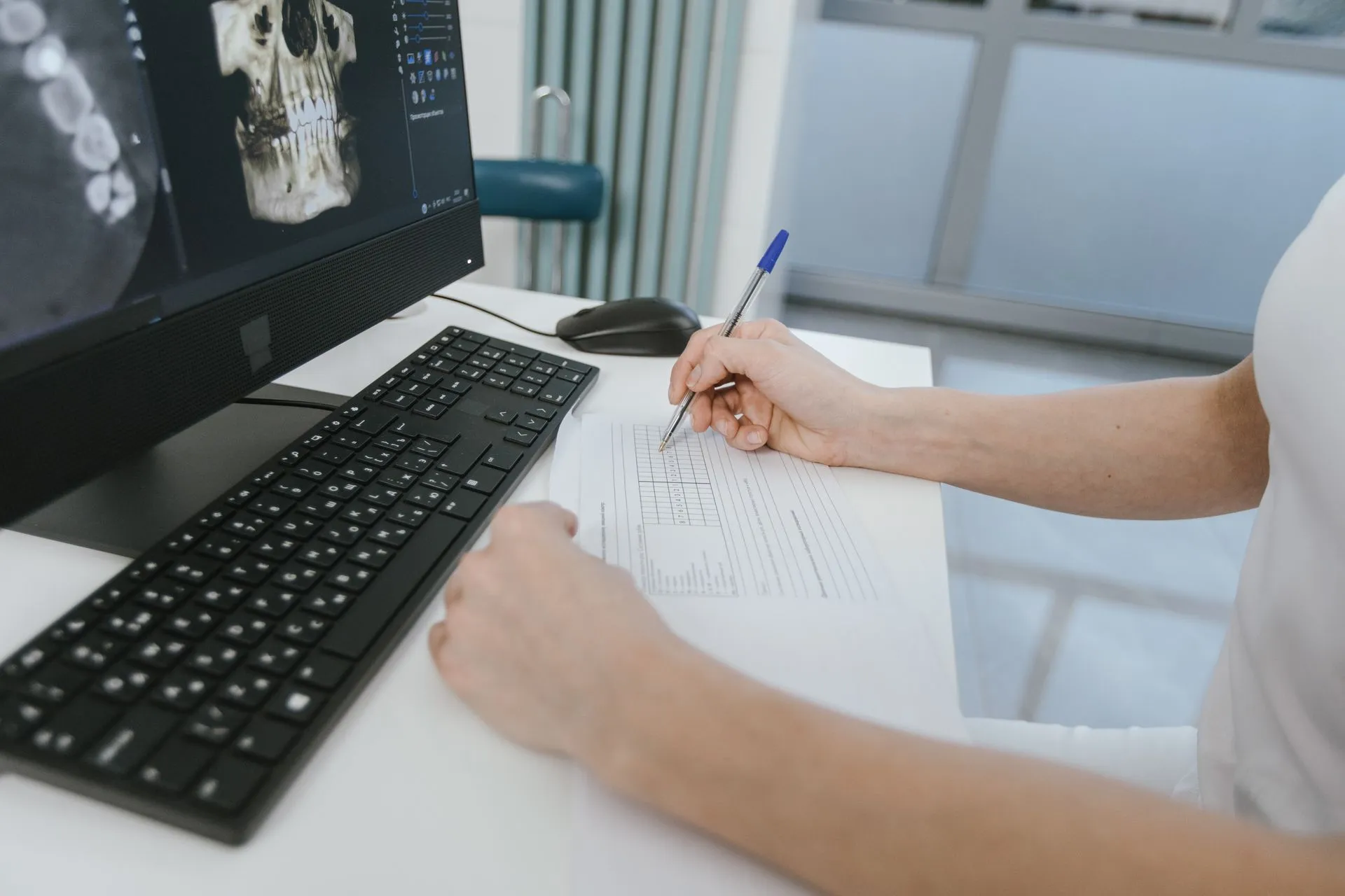 Close-up of a healthcare worker analyzing x-ray results and taking notes on a computer desk, illustrating DC Medicaid agency reports health data exposure of 399,086 beneficiaries as