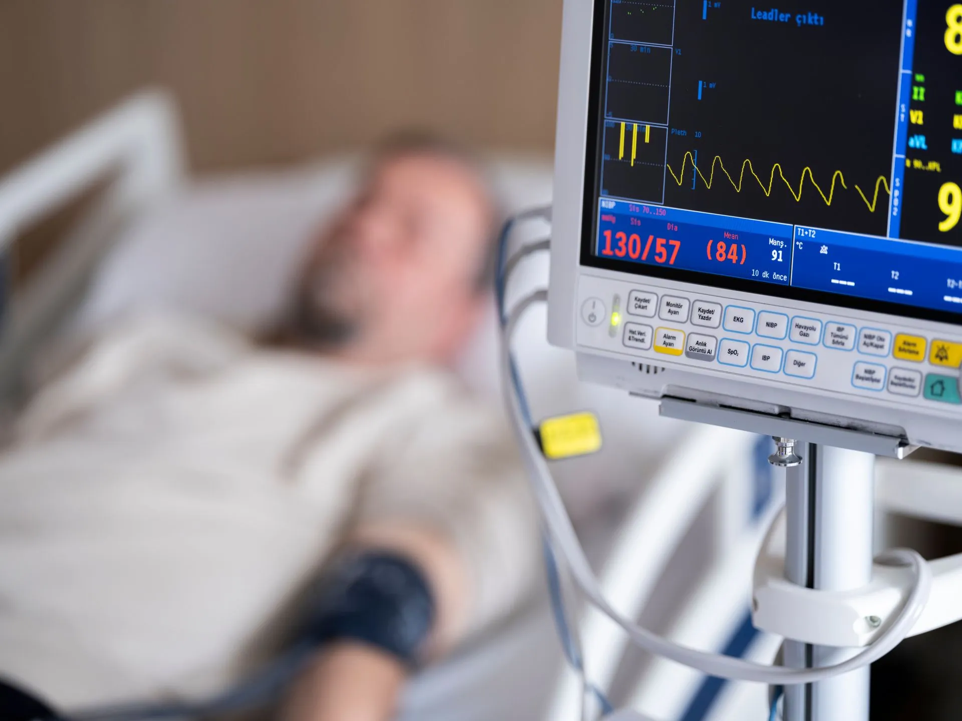 Patient in hospital bed with heart monitor showing blood pressure and heart rate, illustrating Healthleap raises $38 million for AI that flags hospital patients with missed conditions