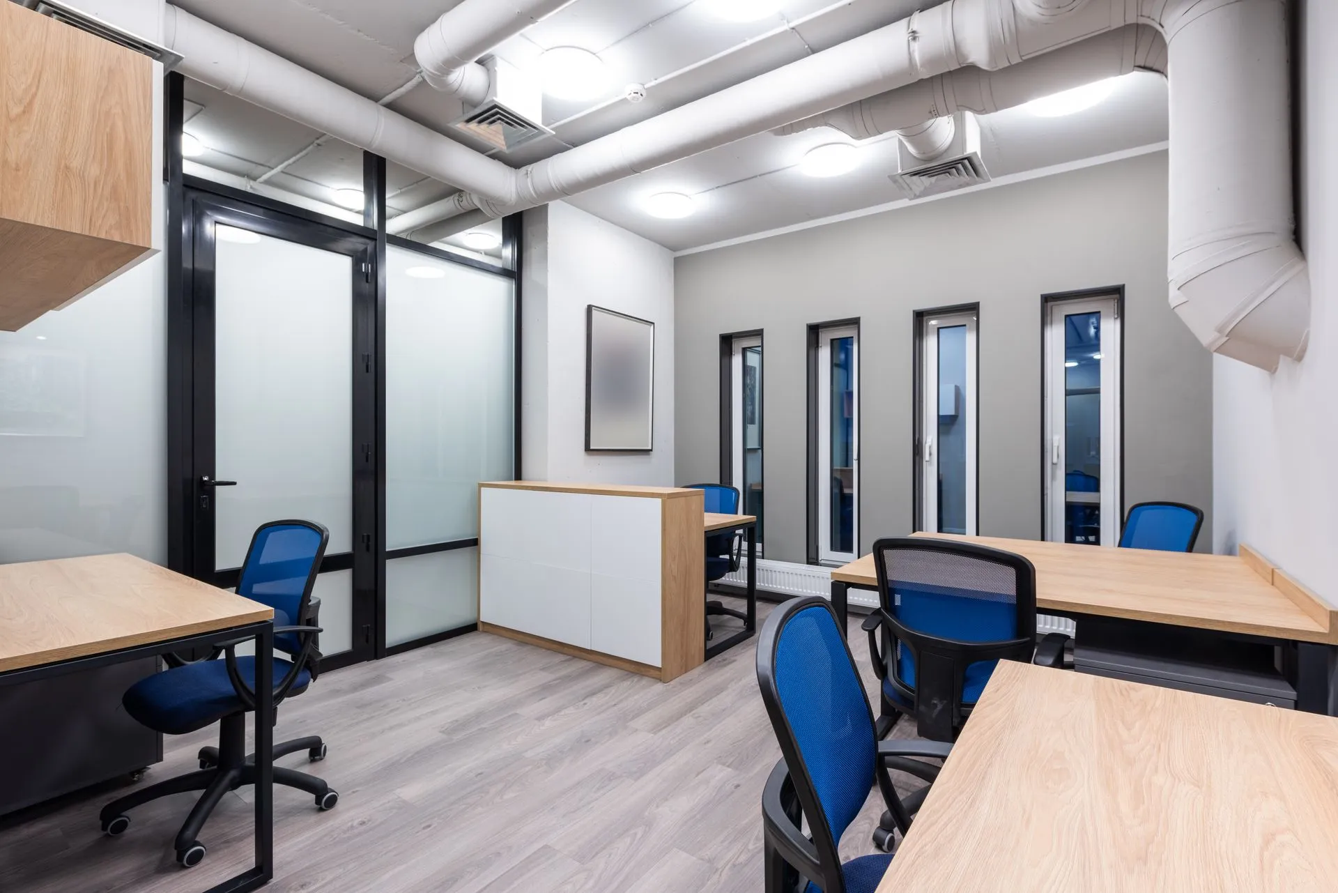 Interior of new contemporary spacious workplace with wooden desks and blue office chairs, illustrating HSBC plans to cut around 70% of UK wealth advisers in AI push, FT reports