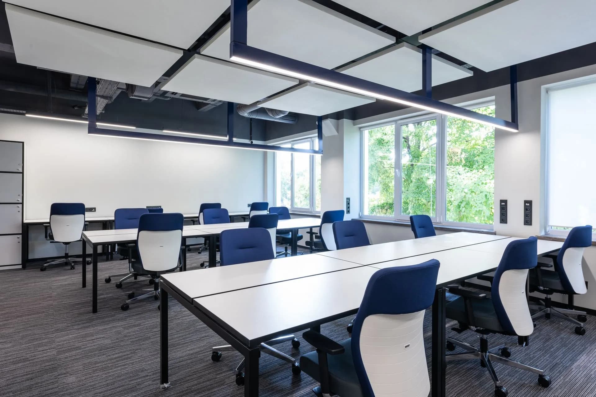 White long tables with comfortable blue armchairs placed in spacious open space office with big window in modern business, illustrating HubSpot layoffs cut about 660 jobs, or 7% of staff, with up
