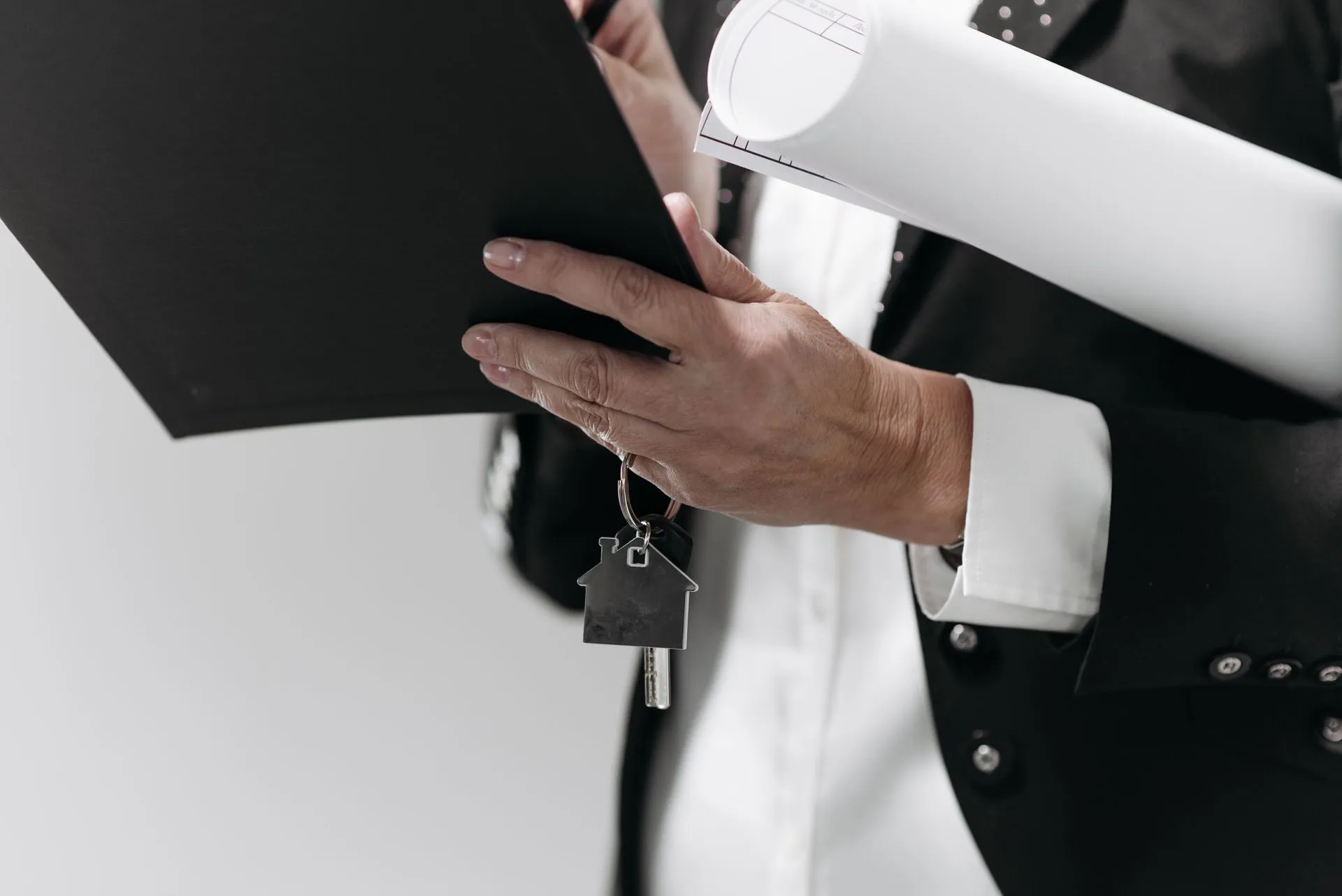 Close-up of a business professional holding a house key and architectural plans, symbolizing real estate, illustrating HUD opens Fair Housing Act probe of Wells Fargo's Black